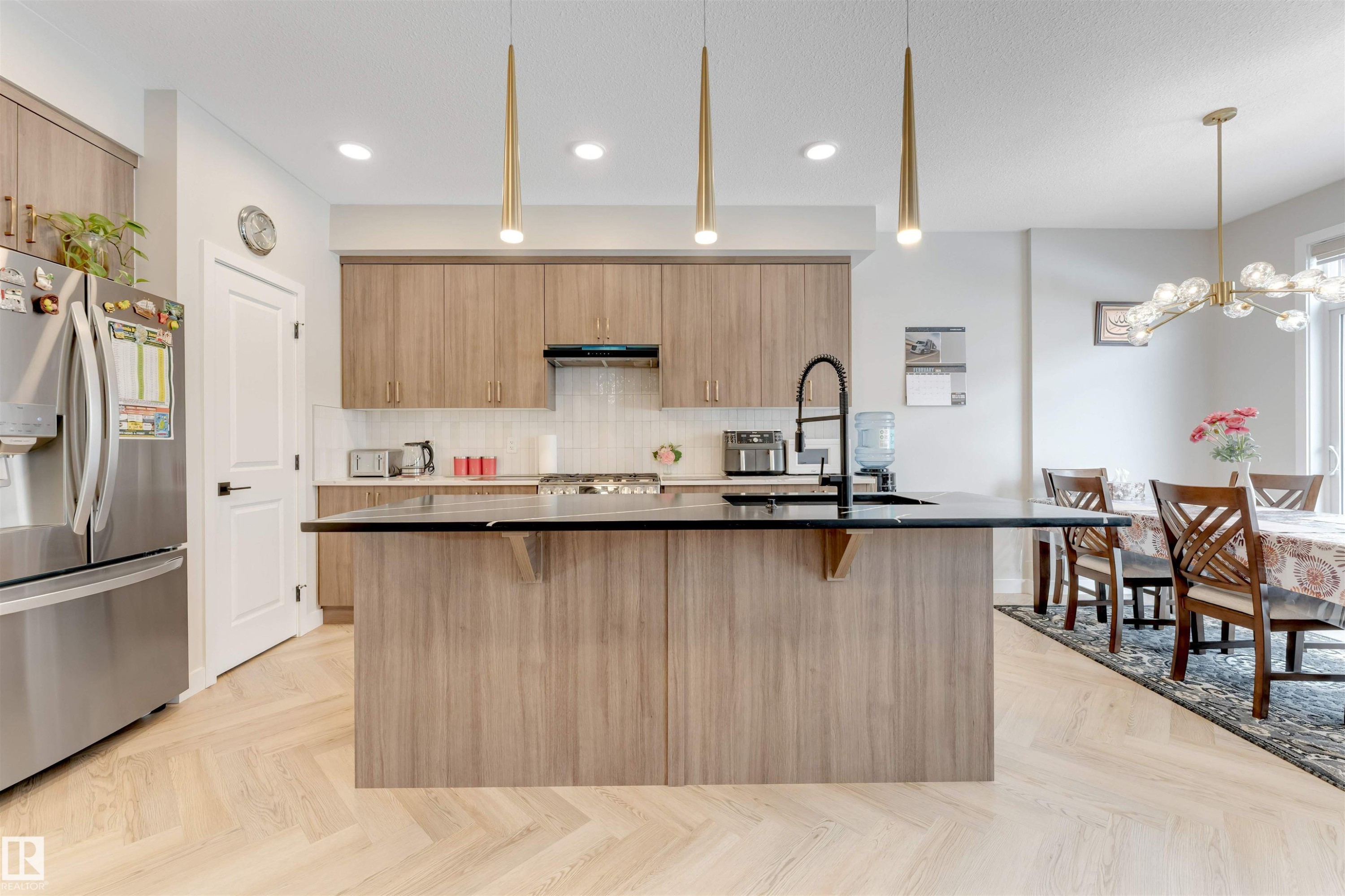 Kitchen featuring a large island with a dark countertop, light wood-finish cabinetry, stainless steel appliances, and a white tile backsplash - 6404 27 Avenue, Edmonton, AB - Indoor Photo Showing Kitchen With Upgraded Kitchen