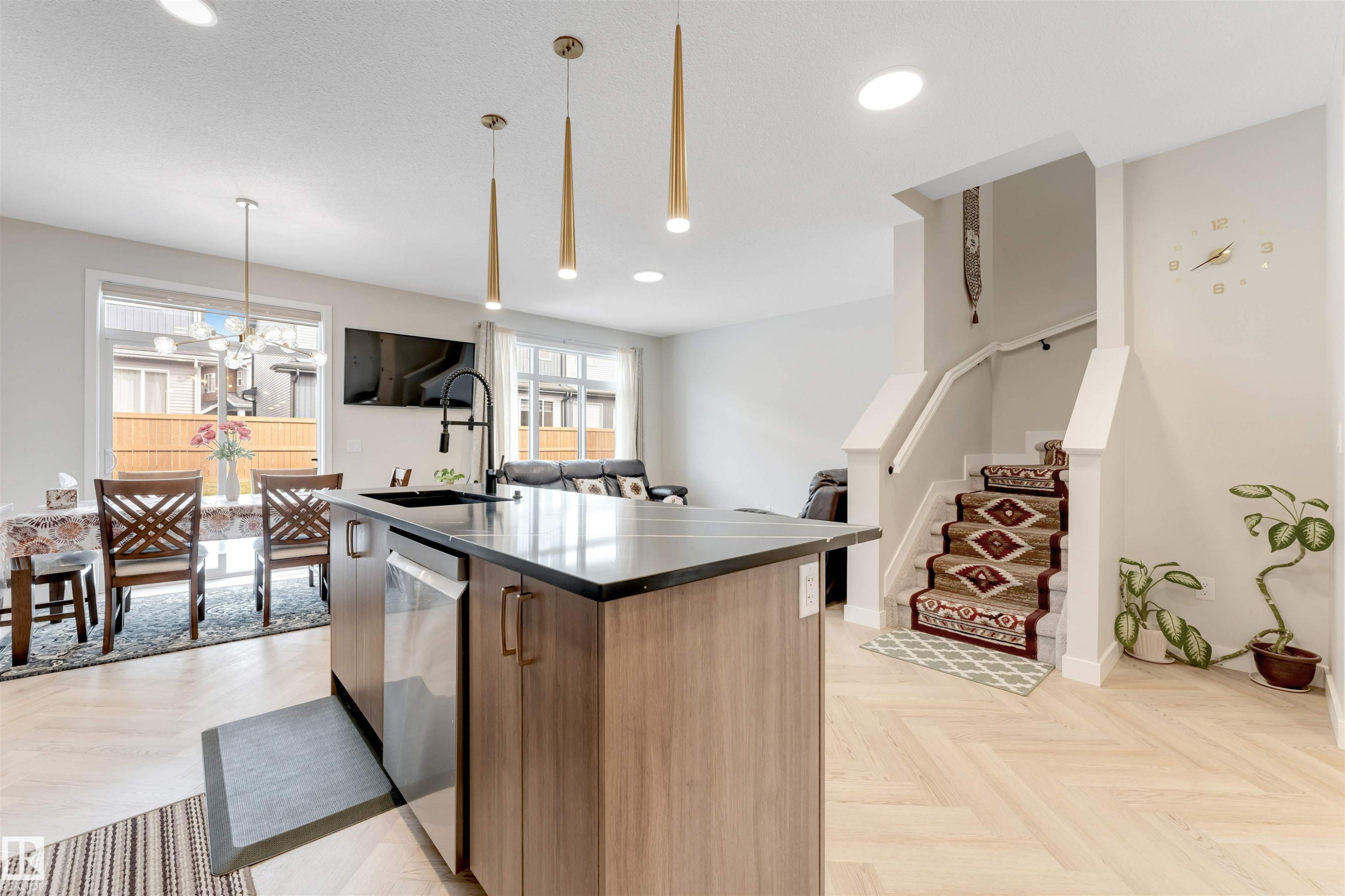 Modern kitchen island featuring a dark countertop, undermount sink with a black faucet, and integrated stainless steel appliances - 6404 27 Avenue, Edmonton, AB - Indoor Photo Showing Kitchen