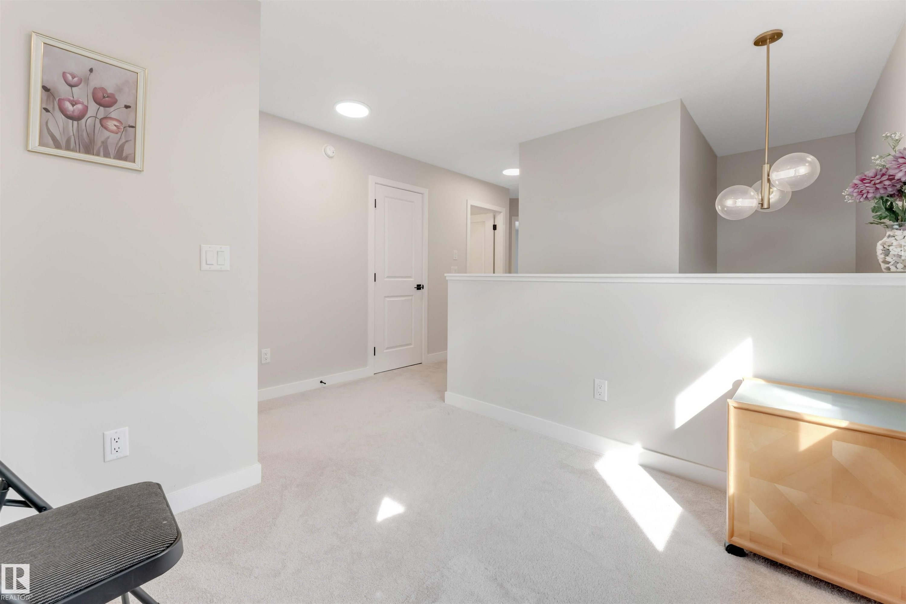 Spacious landing area featuring neutral carpeting, light-toned walls, recessed ceiling lighting, and a contemporary spherical pendant light fixture - 6404 27 Avenue, Edmonton, AB - Indoor Photo Showing Other Room