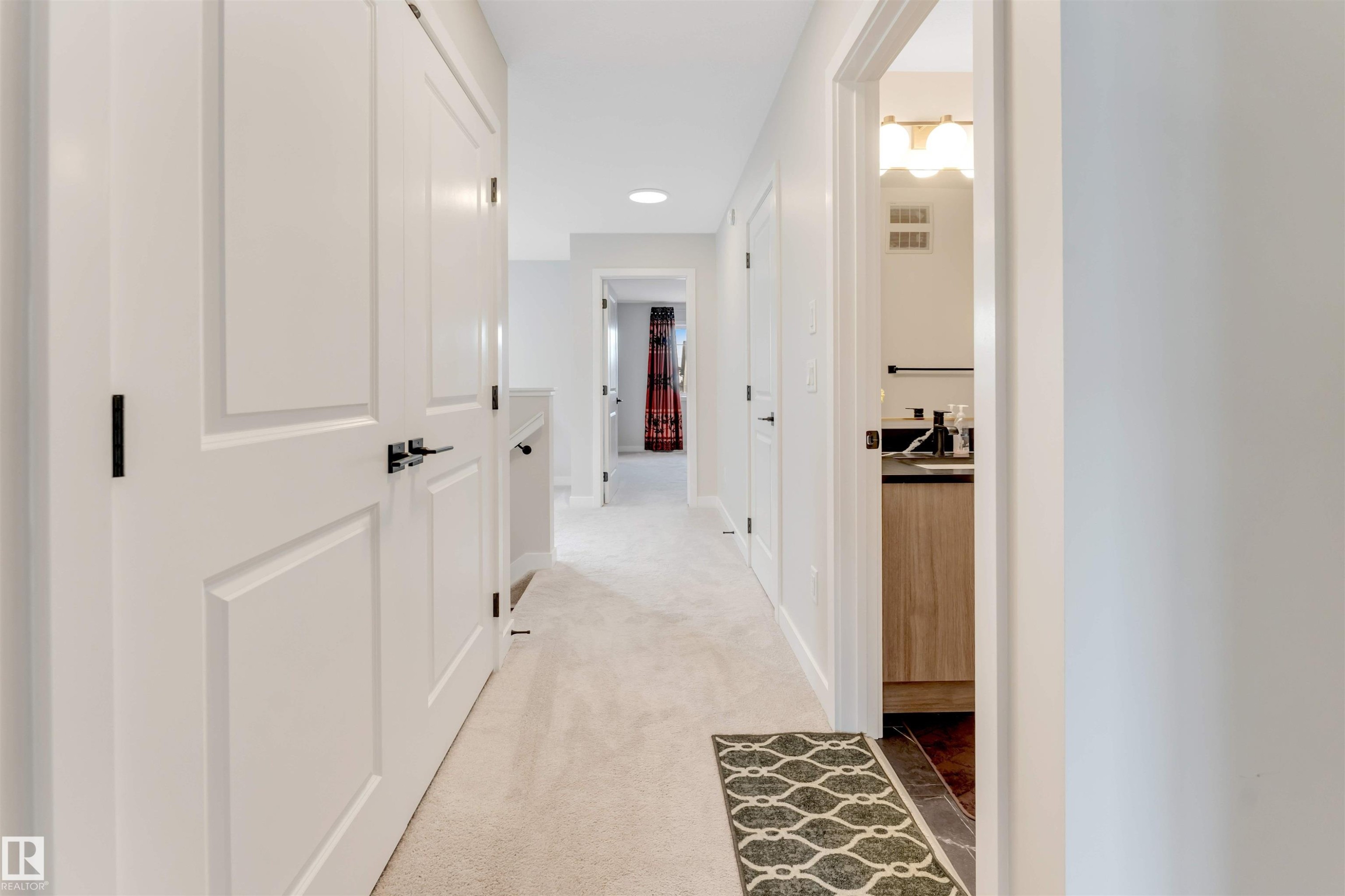 Hallway featuring light-toned carpeting, white paneled doors, and contemporary black hardware - 6404 27 Avenue, Edmonton, AB - Indoor Photo Showing Other Room
