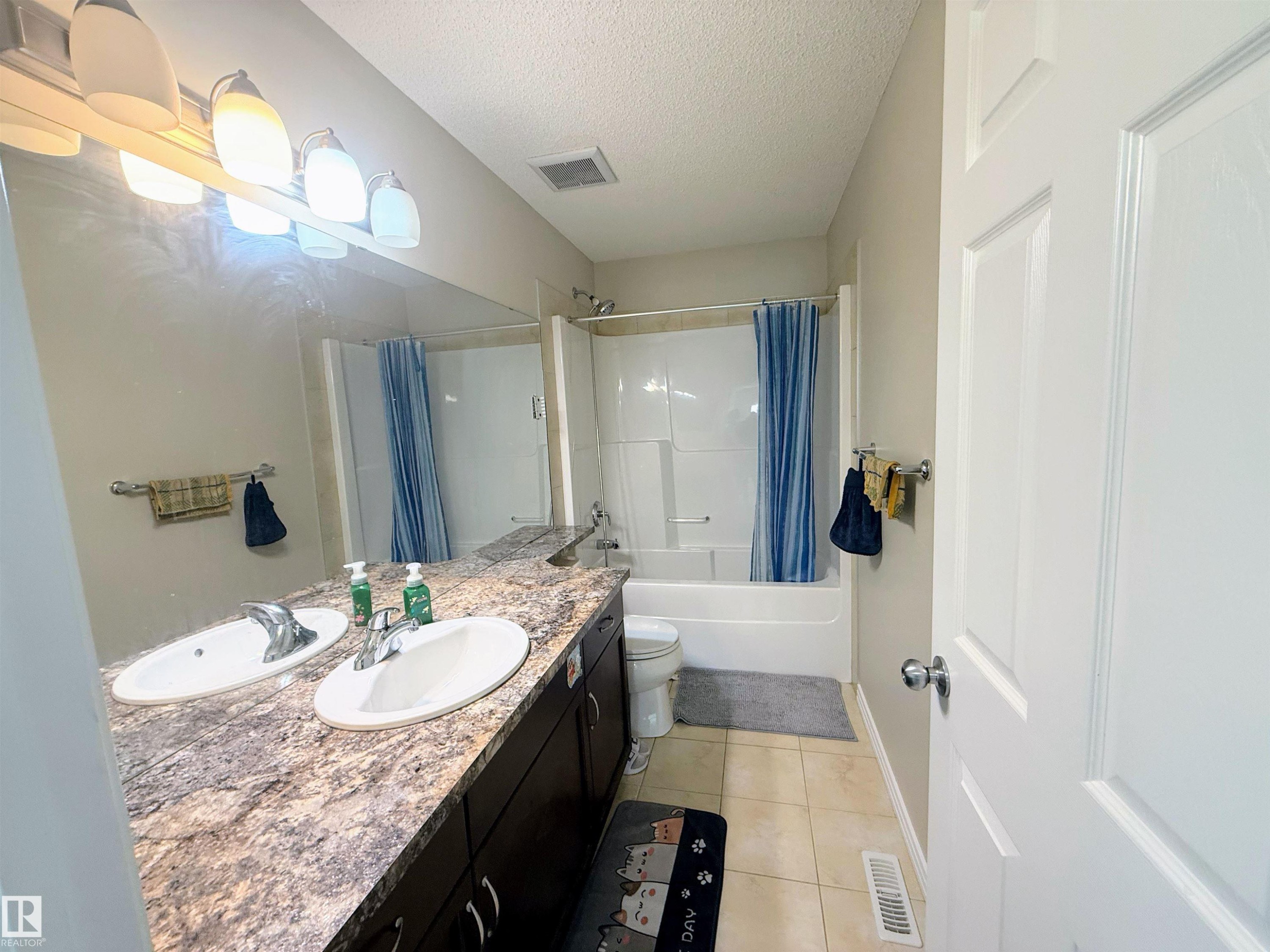 Bathroom featuring a double vanity with two undermount sinks, a speckled countertop, and dark wood-finish cabinetry - 3538 Claxton Crescent, Edmonton, AB - Indoor Photo Showing Bathroom