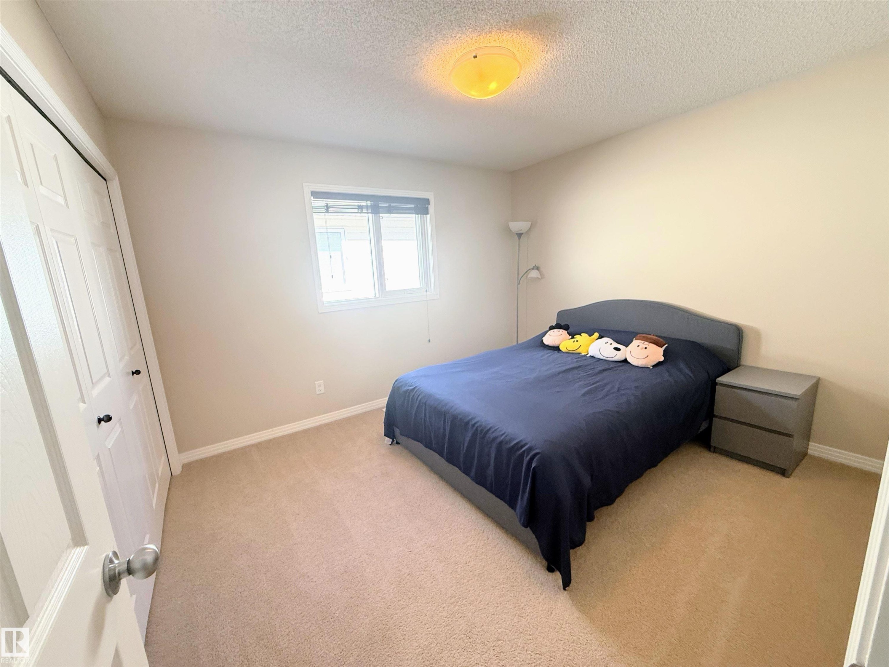 Carpeted room with a double window featuring blinds, a ceiling-mounted light fixture, and bifold closet doors - 3538 Claxton Crescent, Edmonton, AB - Indoor Photo Showing Bedroom