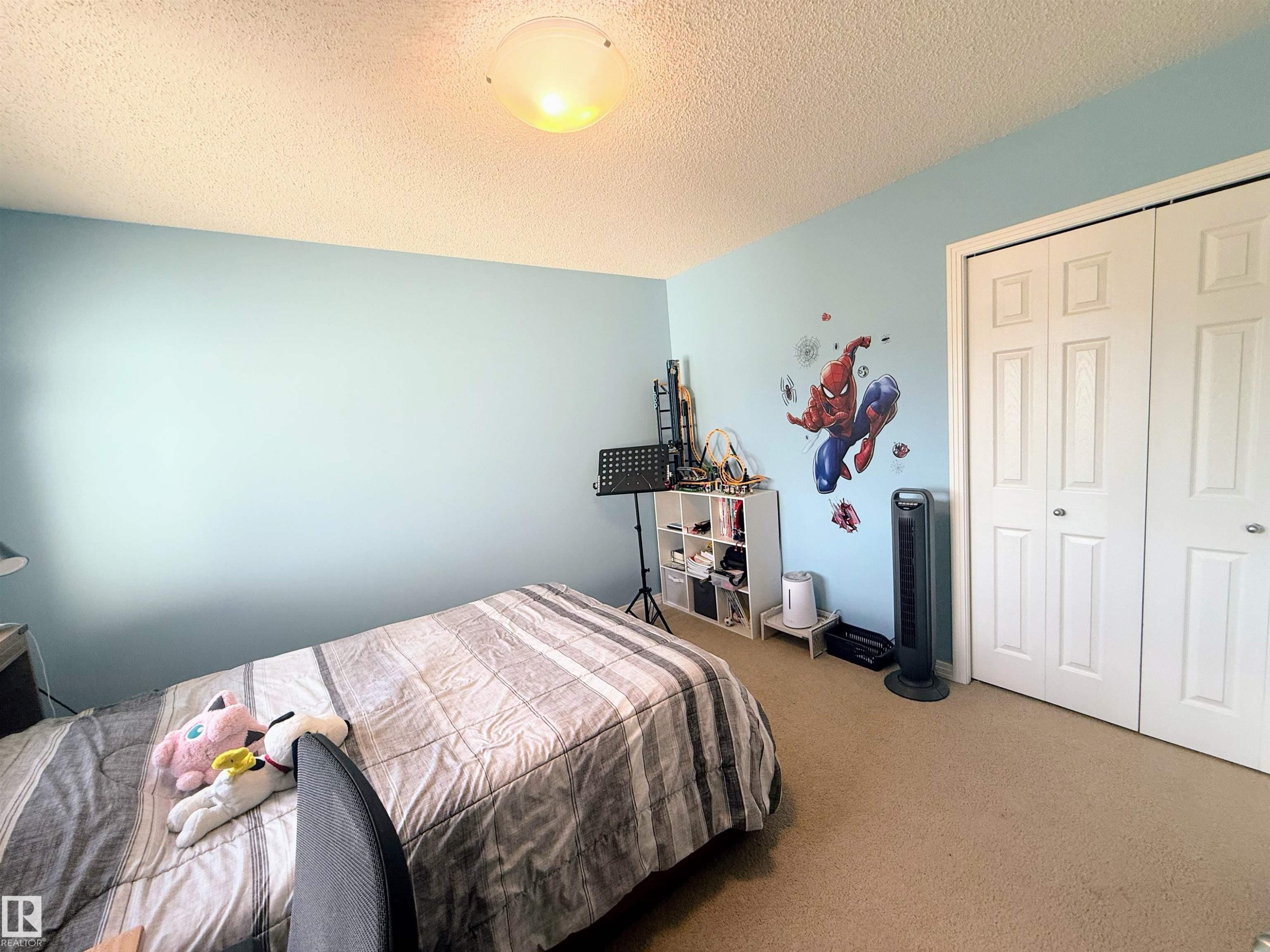 Room featuring light blue walls, carpet flooring, a flush-mount ceiling light fixture, and bifold closet doors - 3538 Claxton Crescent, Edmonton, AB - Indoor Photo Showing Bedroom