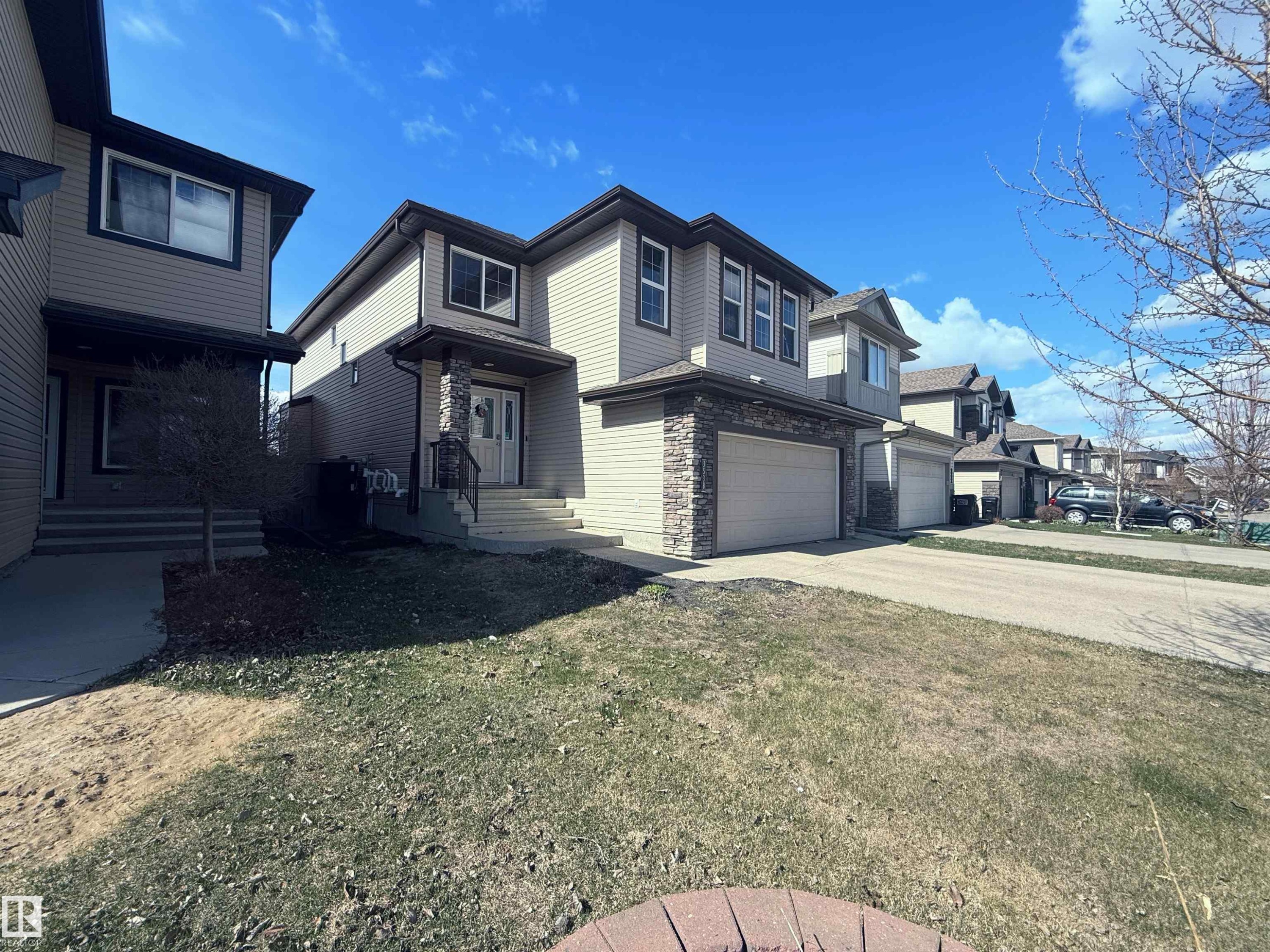 Two-story residence featuring light-colored siding, a stone facade, and a two-car garage - 3538 Claxton Crescent, Edmonton, AB - Outdoor