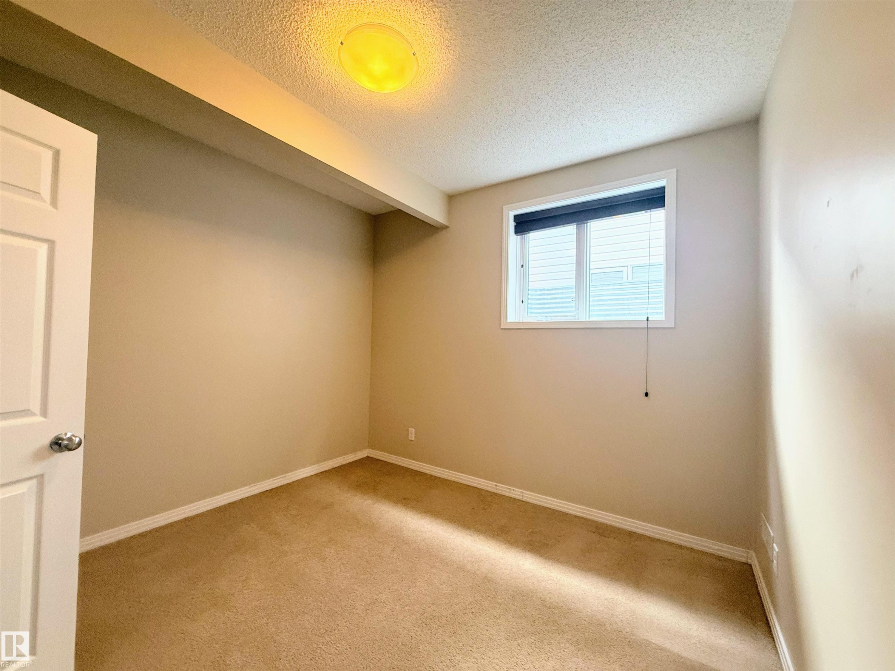 Carpeted room featuring a window with blinds, beige walls, white trim, and a ceiling-mounted light fixture - 3538 Claxton Crescent, Edmonton, AB - Indoor Photo Showing Other Room