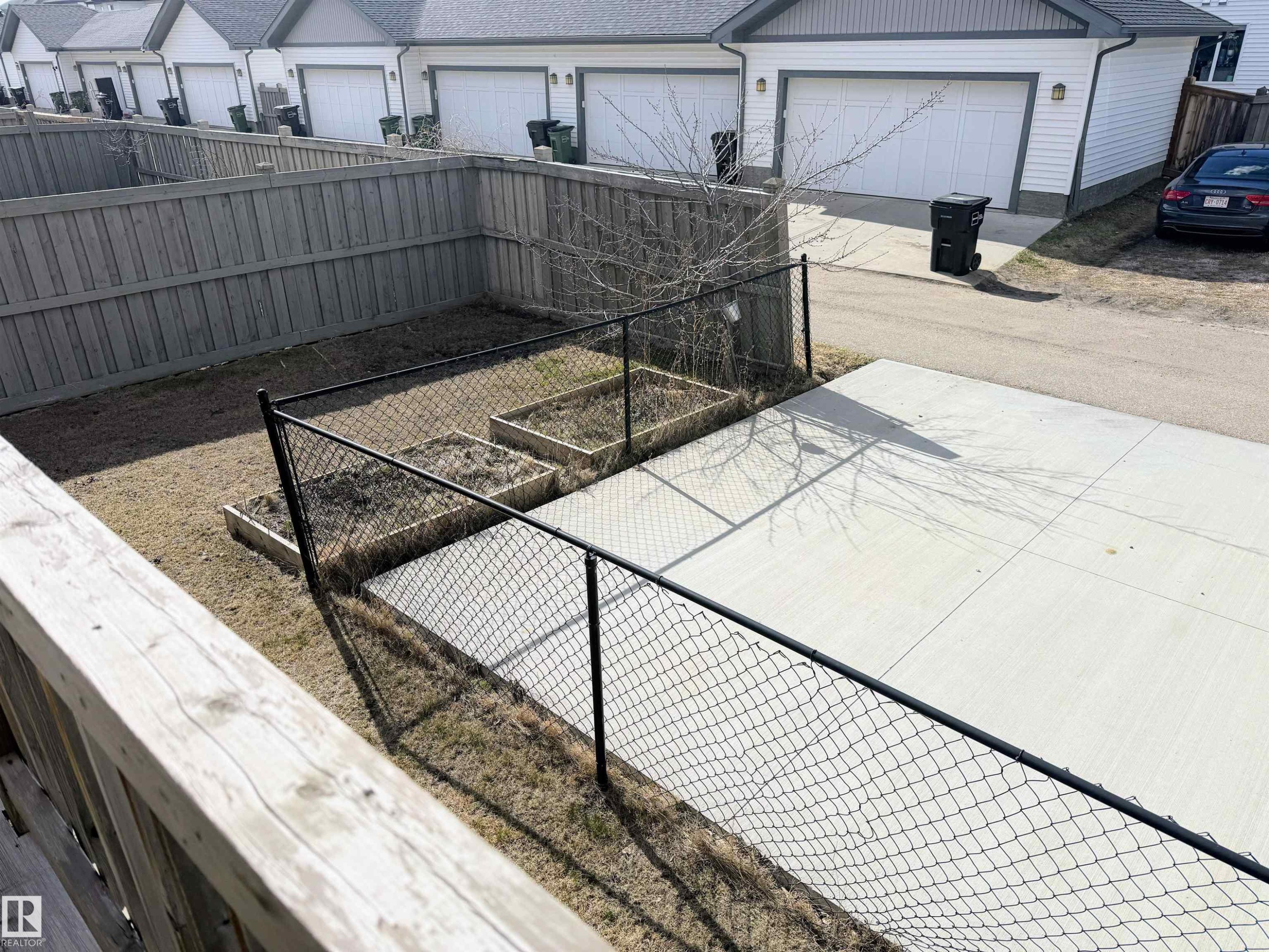 Fenced backyard featuring a concrete patio, two raised garden beds, and a wood privacy fence - 3538 Claxton Crescent, Edmonton, AB - Outdoor With Exterior