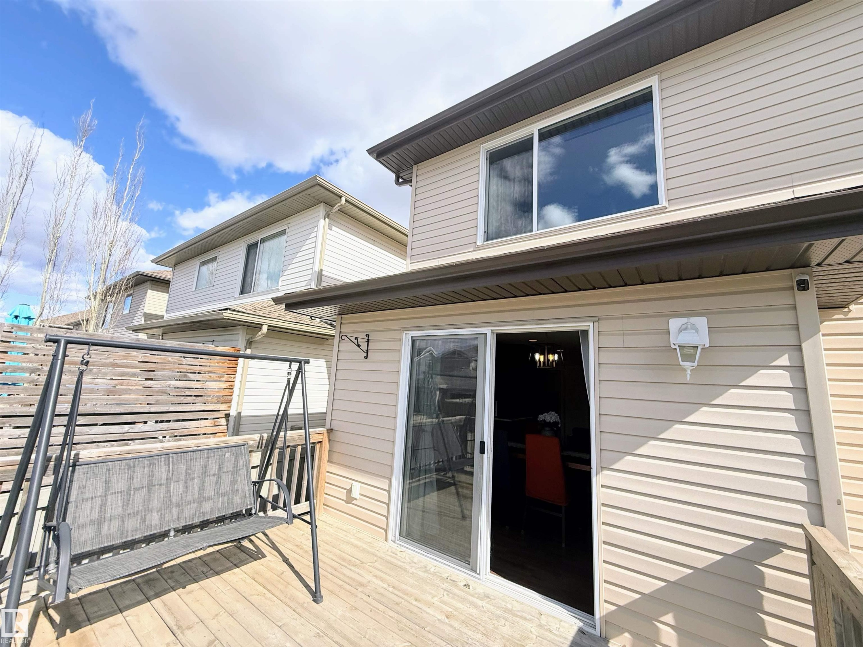 Wood-finish deck with a privacy screen and sliding glass patio doors - 3538 Claxton Crescent, Edmonton, AB - Outdoor With Exterior