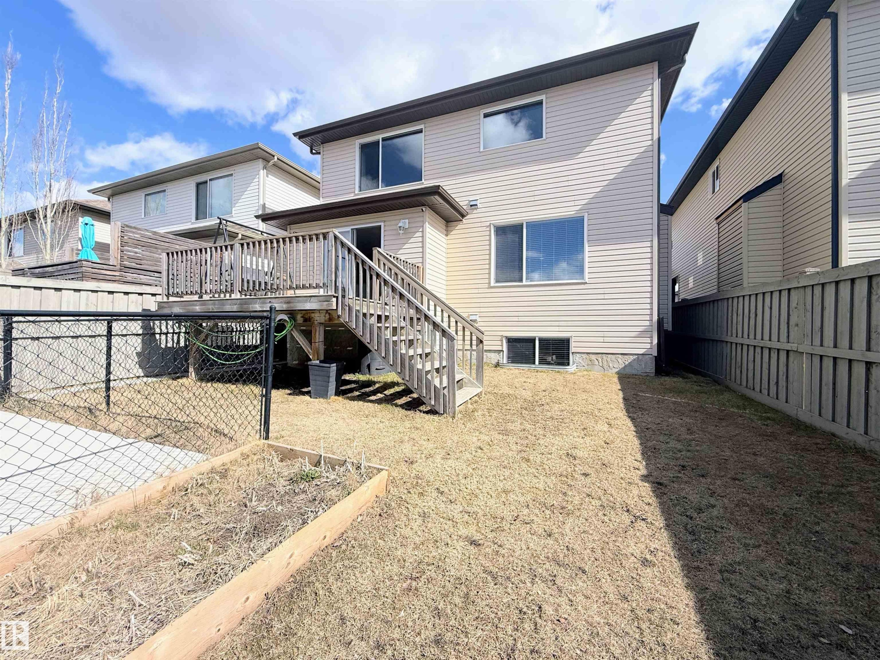 Rear exterior featuring a wood deck with stairs, vinyl siding, and a fenced yard - 3538 Claxton Crescent, Edmonton, AB - Outdoor With Exterior