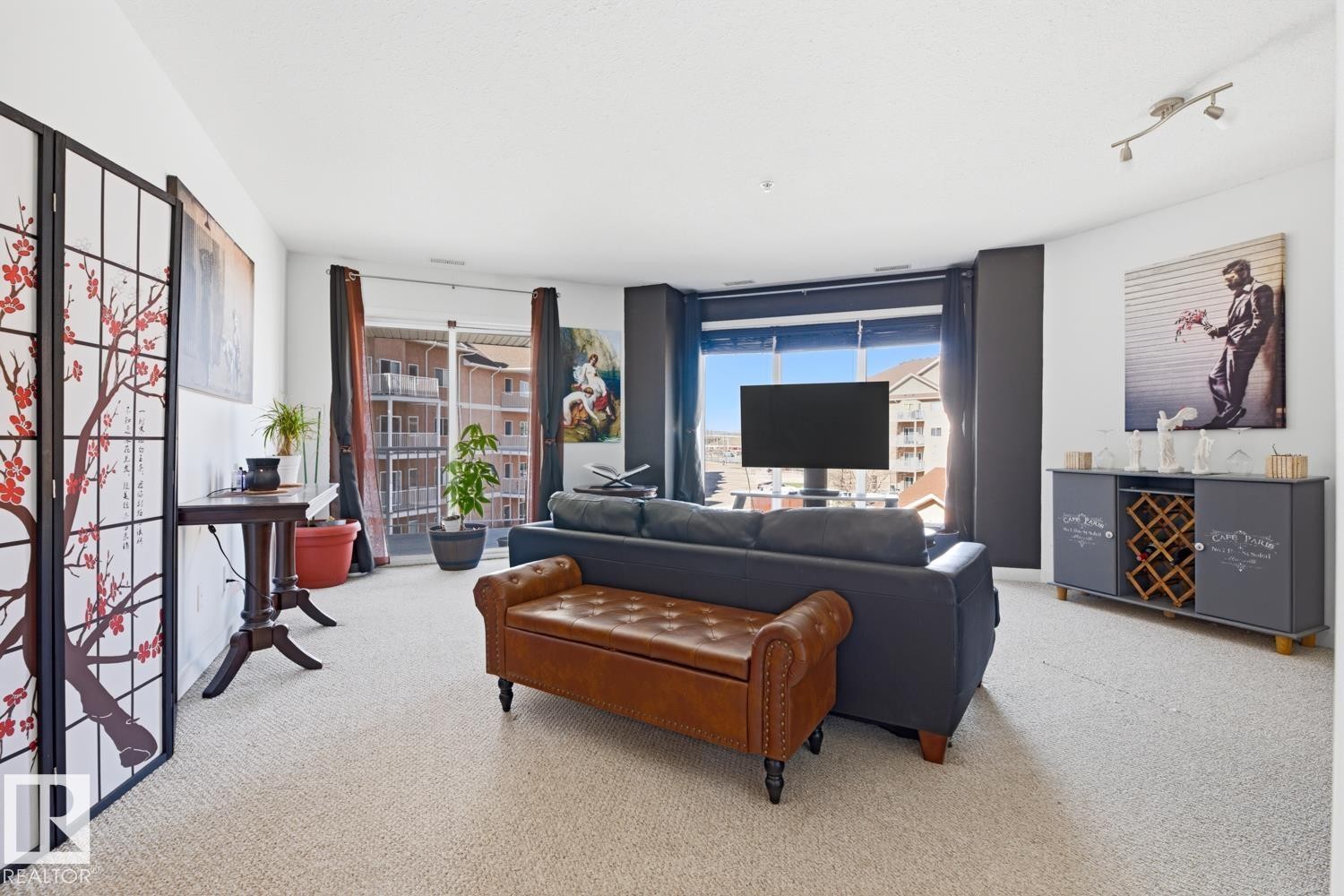 Open-concept living area featuring light-colored carpeting, white walls, and track lighting - 304 4312 139 Ave, Edmonton, AB - Indoor