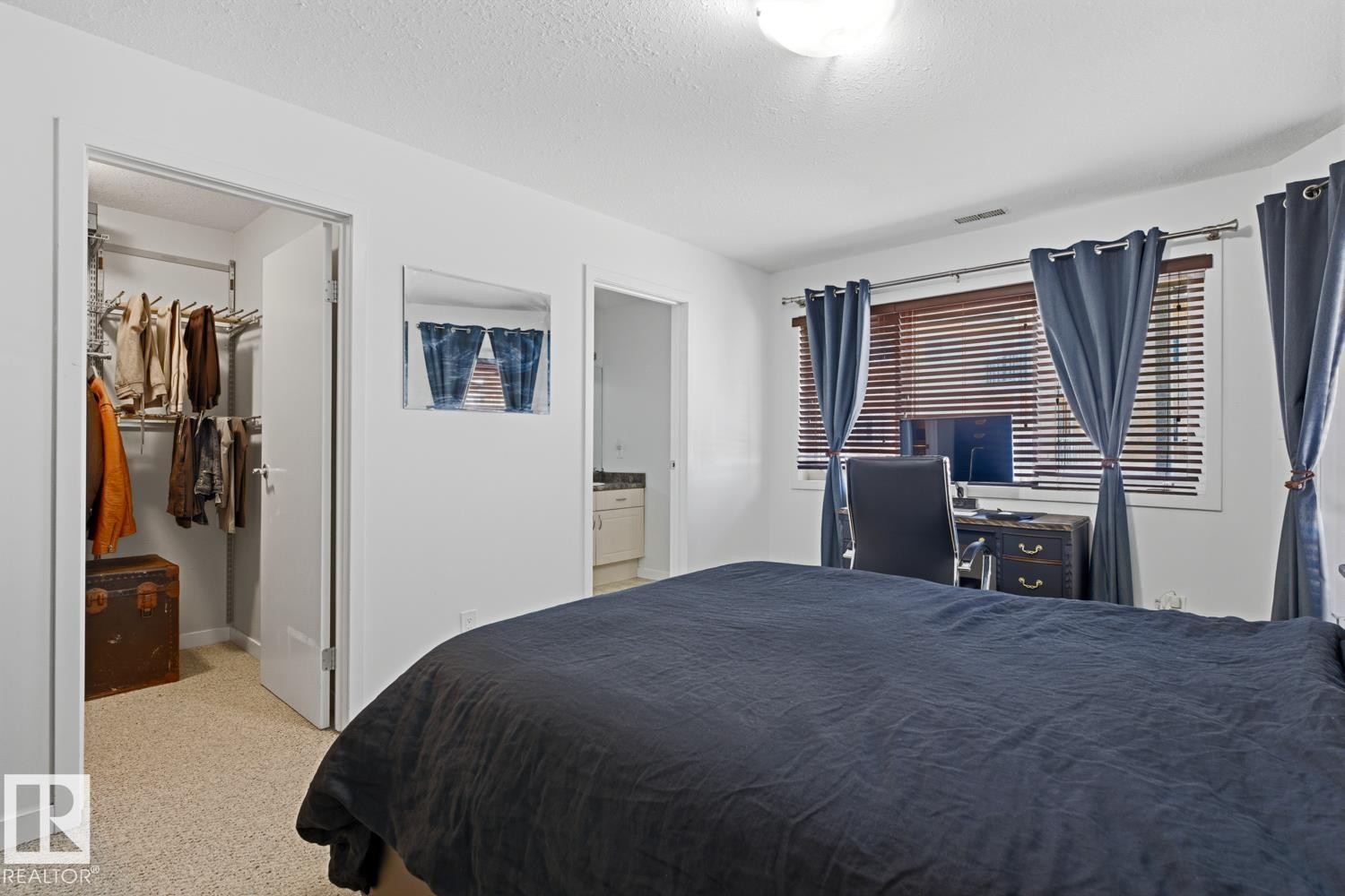 Bedroom featuring neutral wall paint, textured carpeting, and a window with wood-finish blinds - 304 4312 139 Ave, Edmonton, AB - Indoor Photo Showing Bedroom