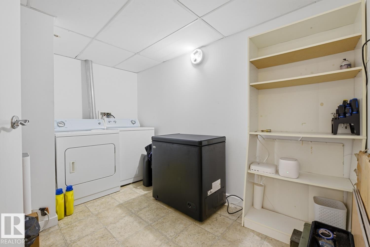 Dedicated laundry area featuring a washer and dryer, tile-finish flooring, and built-in shelving for storage - 304 4312 139 Ave, Edmonton, AB - Indoor Photo Showing Laundry Room