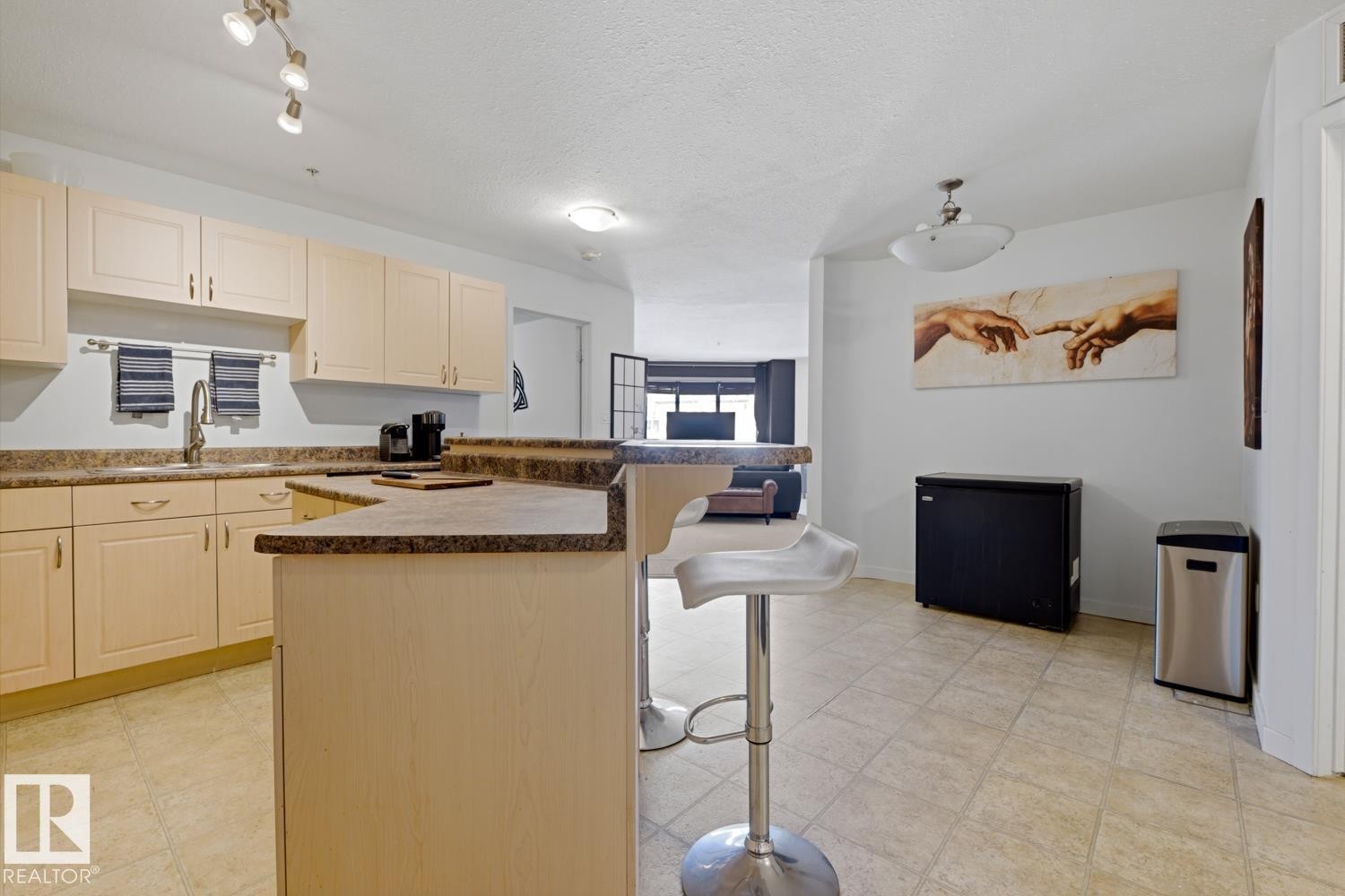 Kitchen featuring light-toned cabinetry, a corner sink with a gooseneck faucet, speckled countertops, and track lighting - 304 4312 139 Ave, Edmonton, AB - Indoor Photo Showing Kitchen With Double Sink