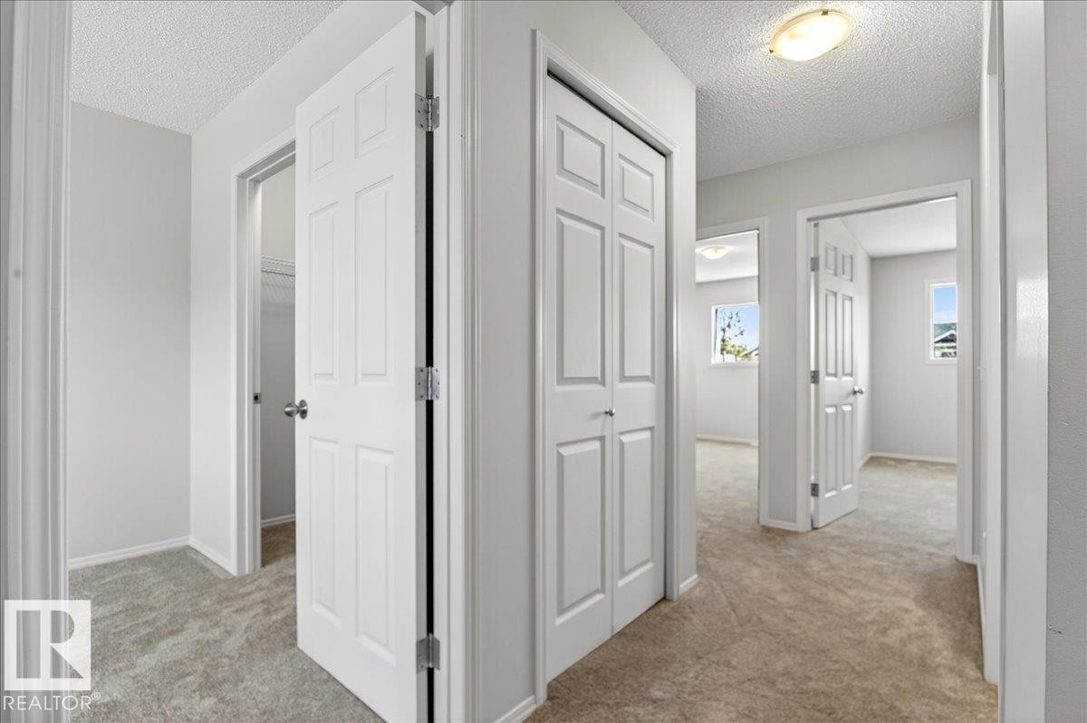 Hallway featuring light-colored carpeting, white paneled doors, and neutral wall paint - #7 18004 89 St Nw, Edmonton, AB - Indoor Photo Showing Other Room