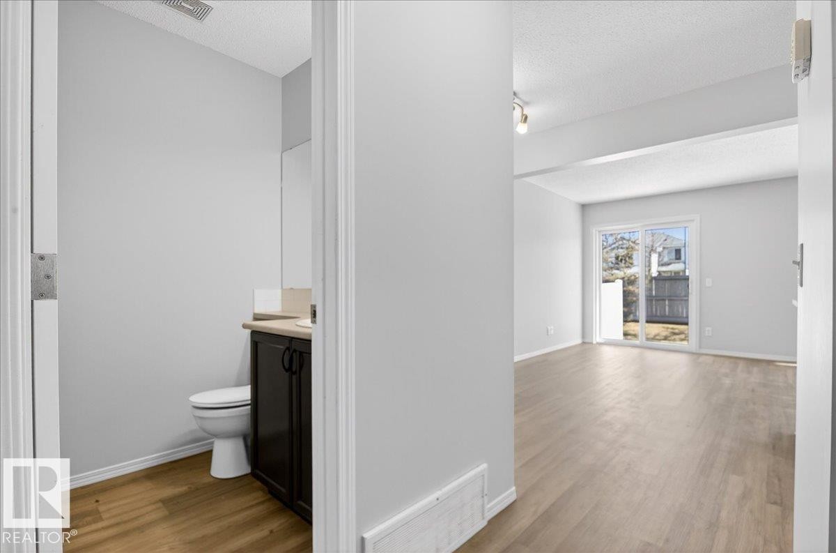 Bright interior featuring wood-finish flooring and light gray walls - #7 18004 89 St Nw, Edmonton, AB - Indoor Photo Showing Bathroom