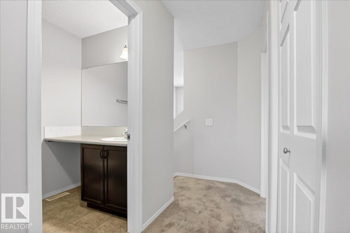 Hallway with neutral carpeting and white painted walls, featuring a bathroom entrance - #7 18004 89 St Nw, Edmonton, AB - Indoor Photo Showing Other Room