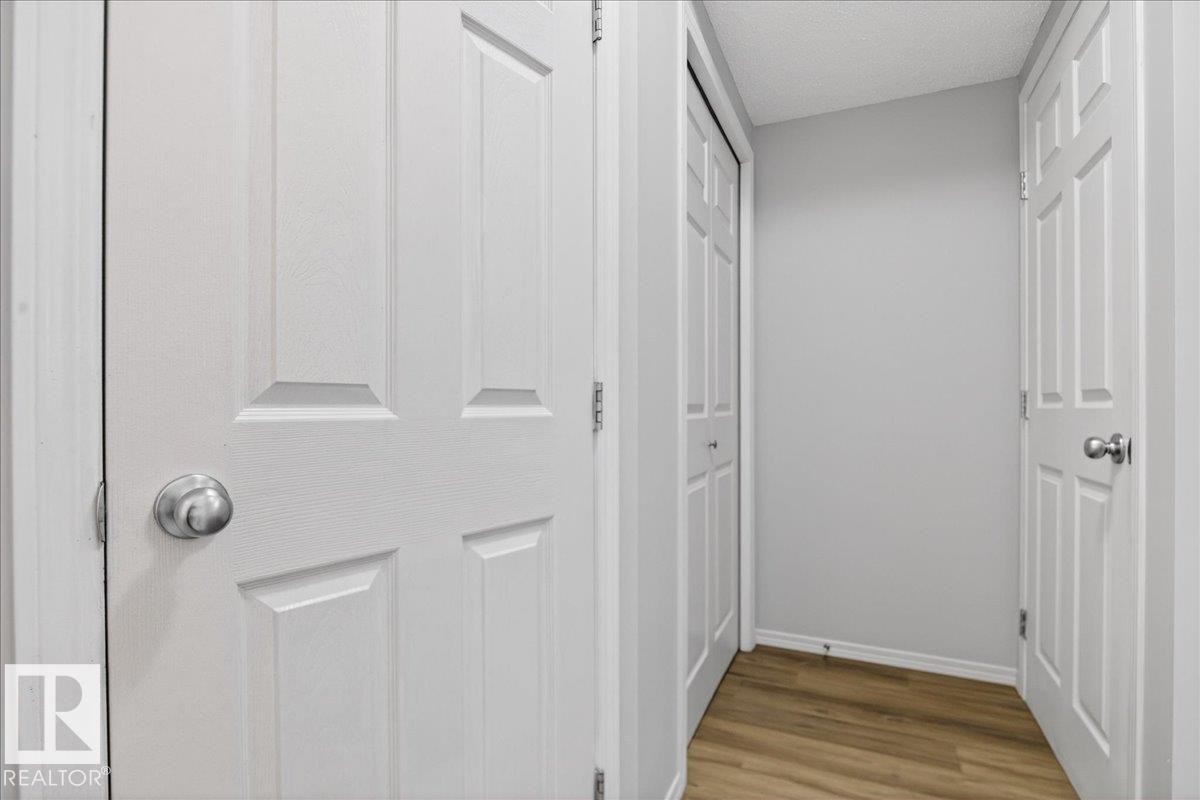 Hallway with wood-finish flooring, light grey painted walls, and white trim - #7 18004 89 St Nw, Edmonton, AB - Indoor Photo Showing Other Room