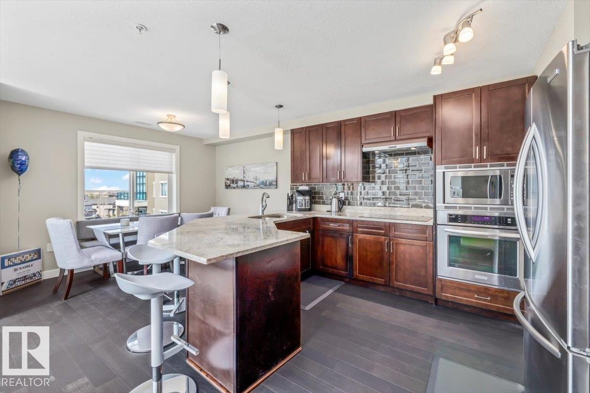 Open-concept living space with dark wood-finish flooring - 513 1230 Windermere Way, Edmonton, AB