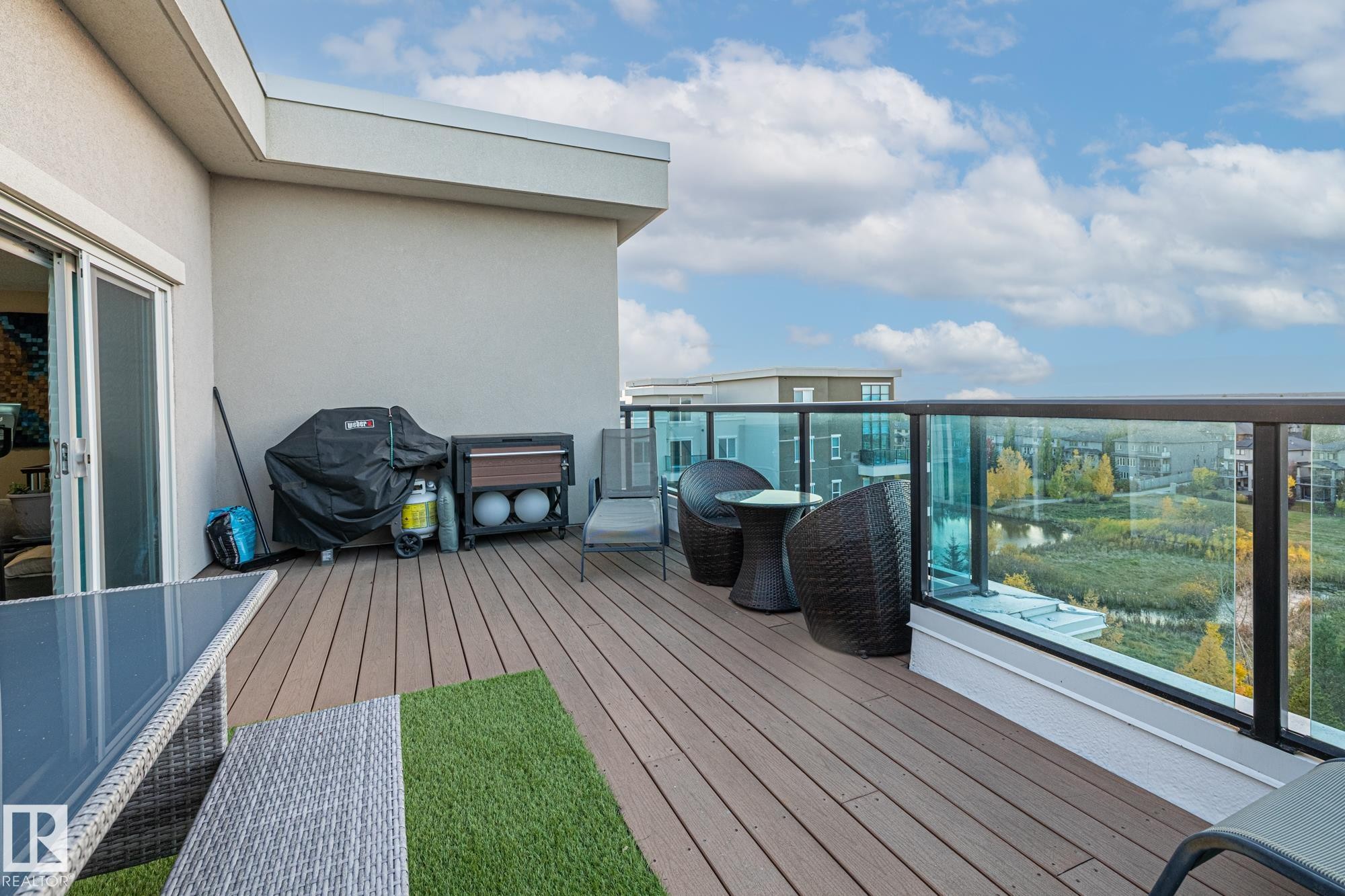 Multilevel exterior featuring a private balcony with blue-tinted glass railings, a full-height window wall, and multiple windows with white trim - 513 1230 Windermere Way, Edmonton, AB