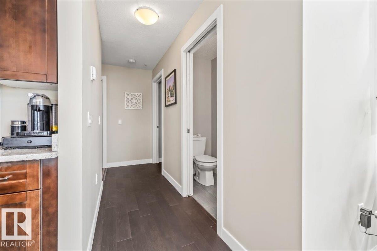 Open-concept living space featuring high ceilings, wood-finish flooring, and a modern kitchen - 513 1230 Windermere Way, Edmonton, AB