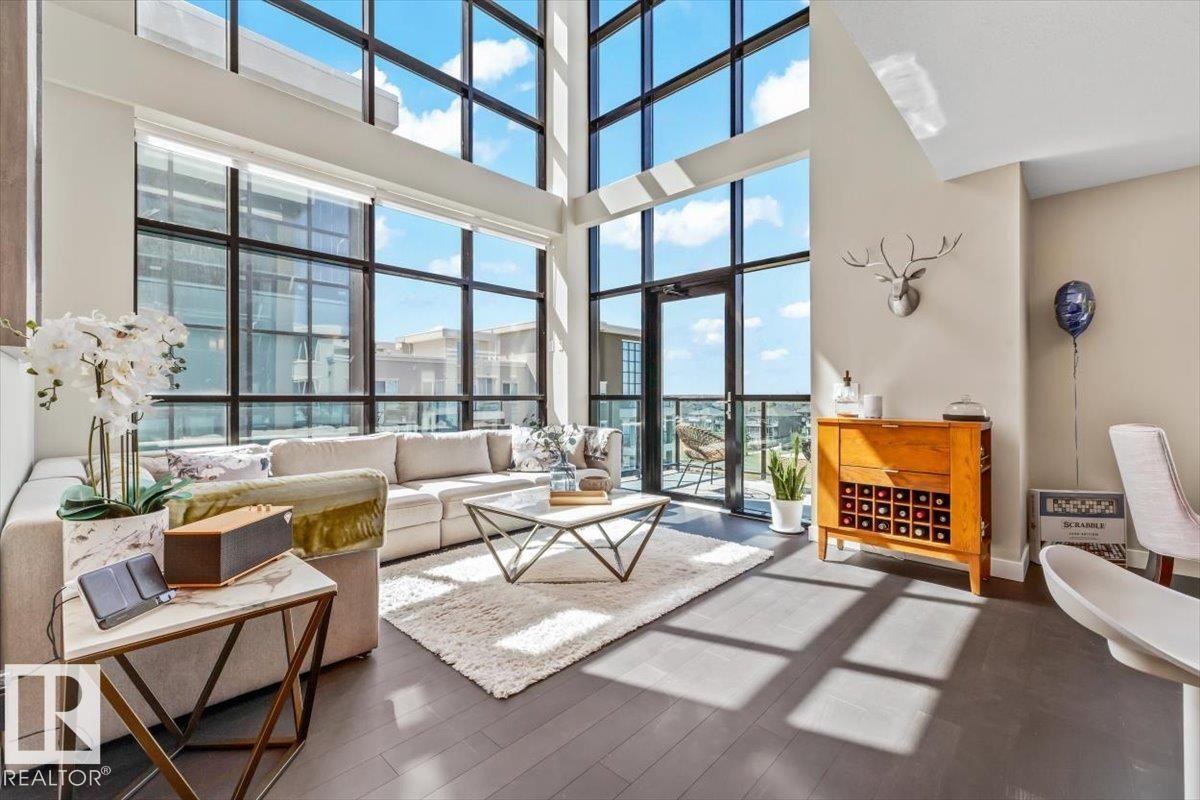 High ceilings and dark wood-finish flooring complement the open-concept living space - 513 1230 Windermere Way, Edmonton, AB