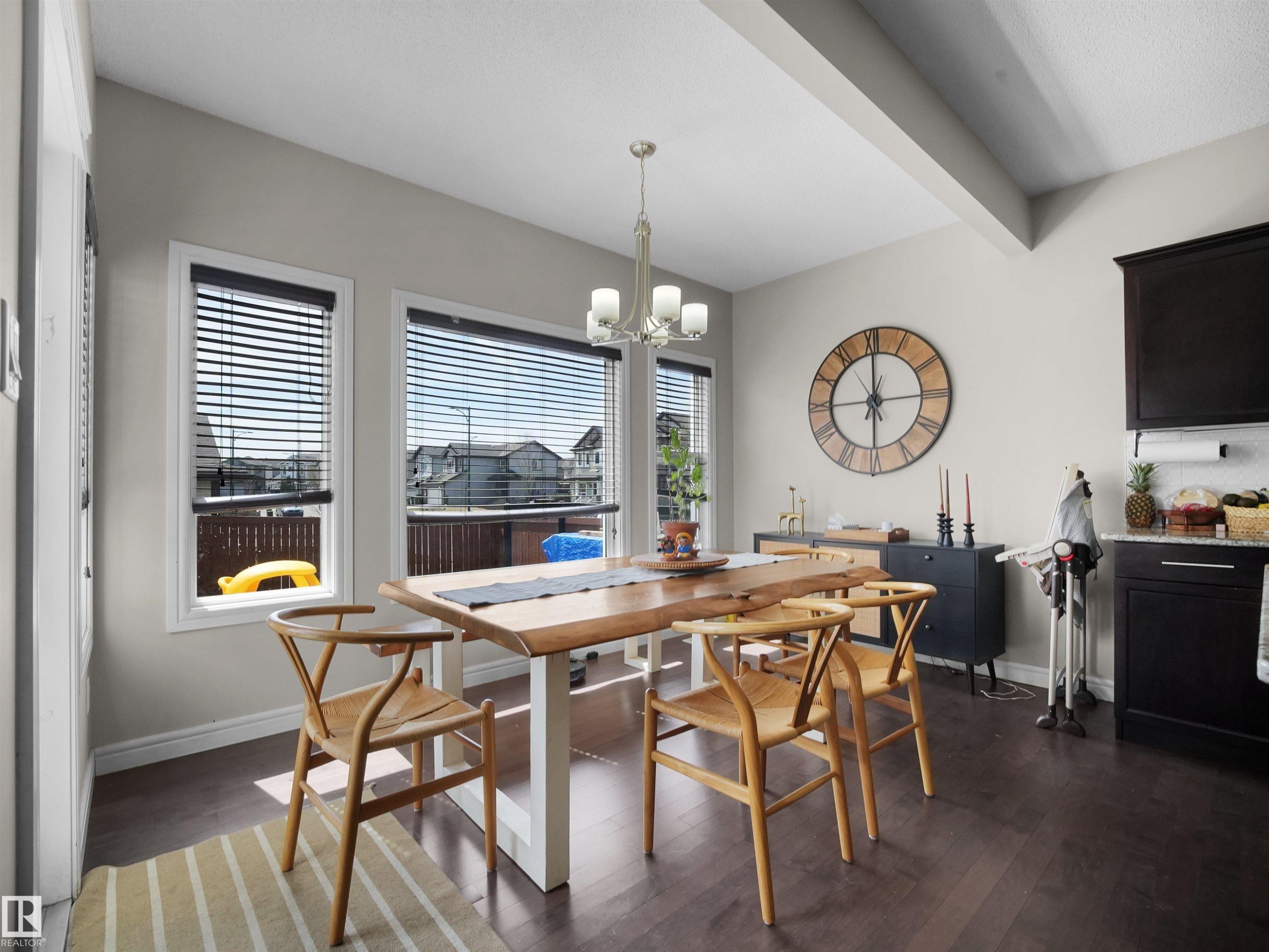 Dining area featuring rich wood-finish flooring and a contemporary chandelier - 3247 15 Avenue Nw, Edmonton, AB