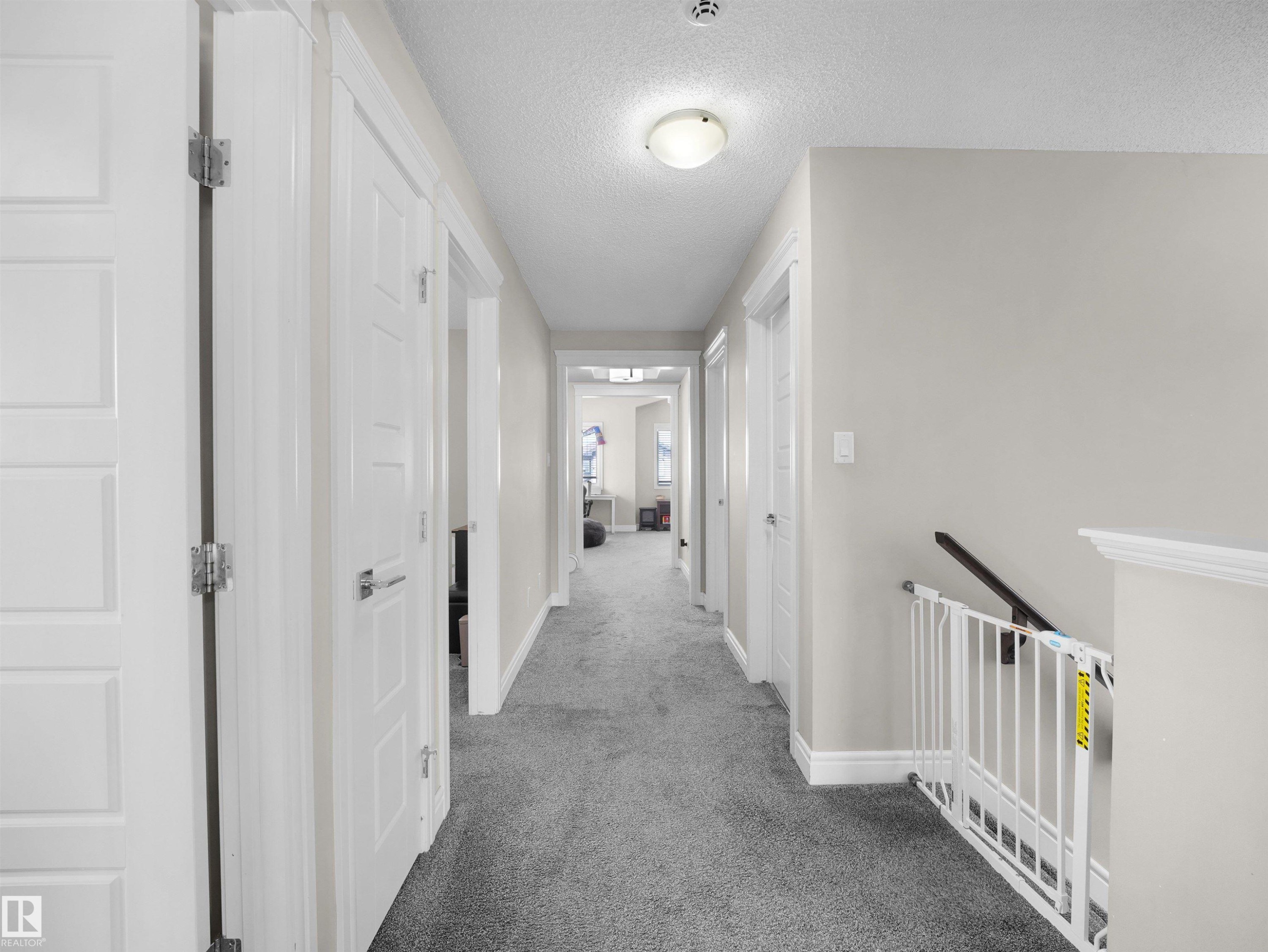 Hallway featuring gray carpeting, light gray walls, and white trim - 3247 15 Avenue Nw, Edmonton, AB