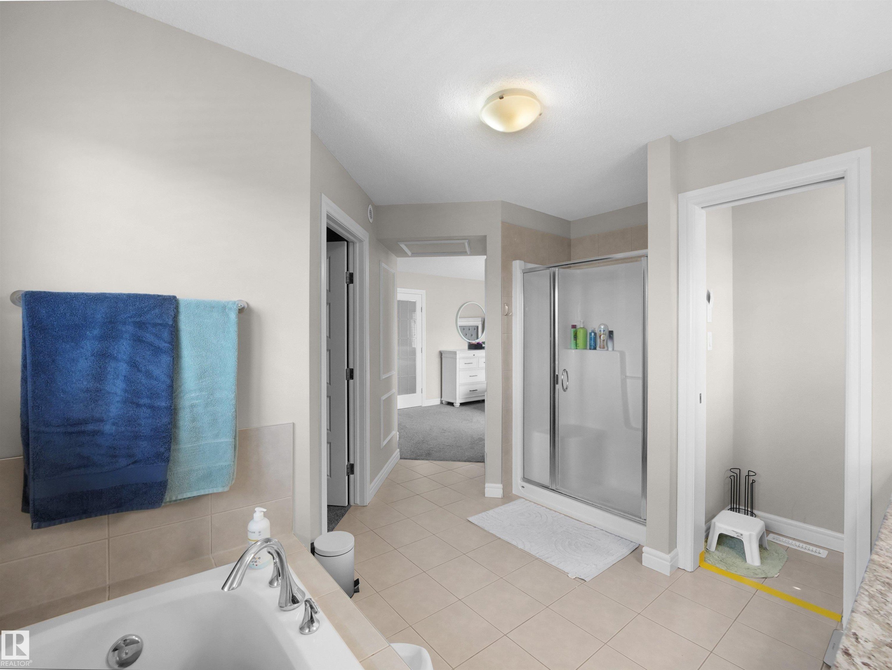 Contemporary bathroom featuring a spacious walk-in shower with a glass enclosure, a built-in bathtub with tile surround, neutral-toned tile flooring, and a flush mount ceiling light fixture - 3247 15 Avenue Nw, Edmonton, AB
