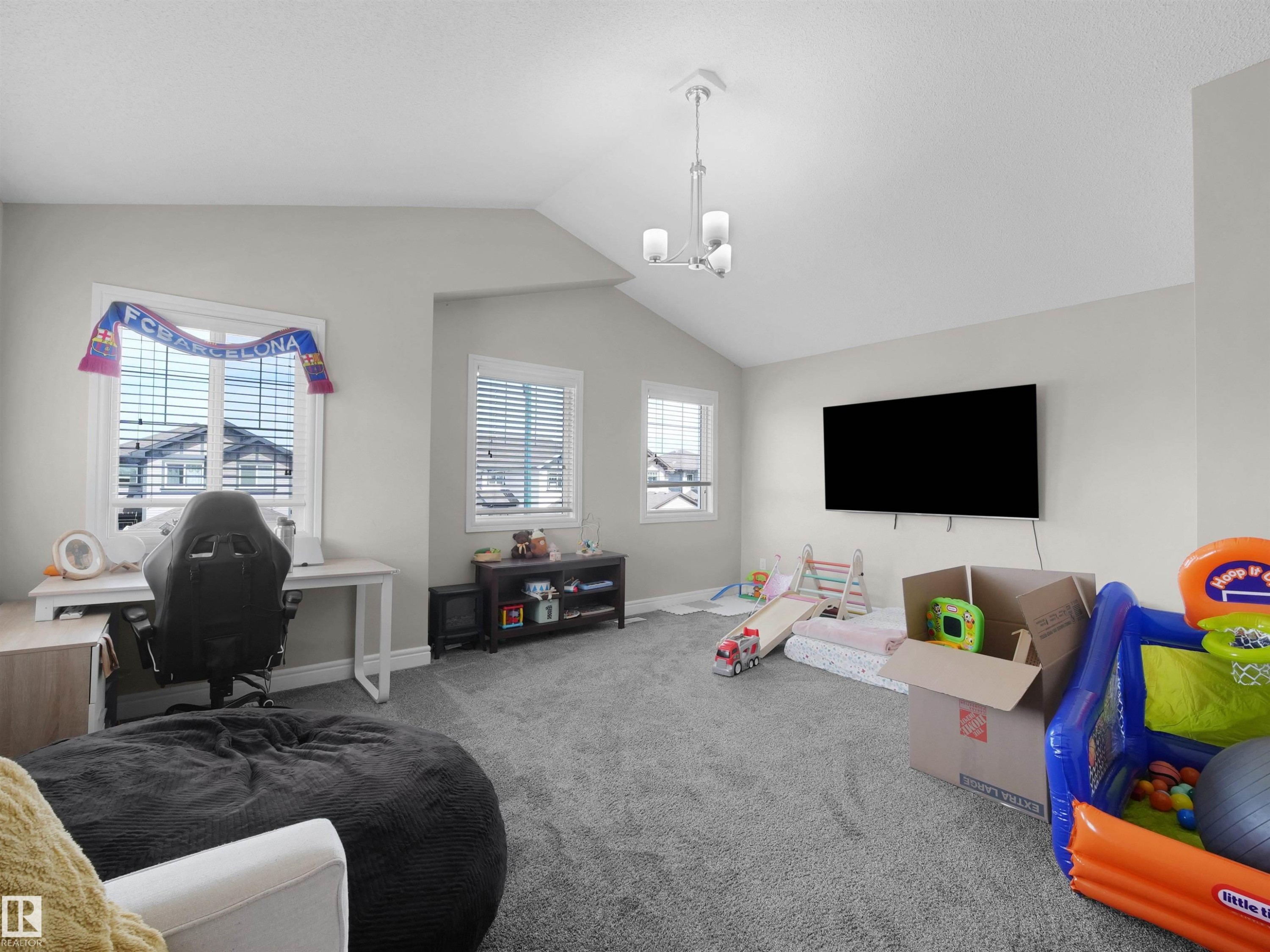 Carpeted room with a vaulted ceiling and a contemporary three-light chandelier - 3247 15 Avenue Nw, Edmonton, AB