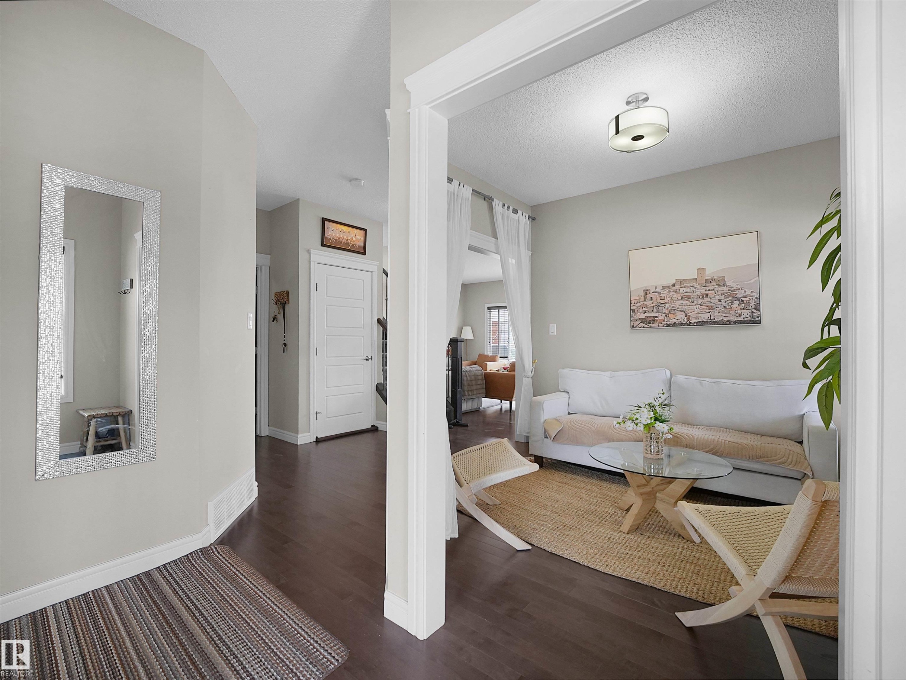 Open concept living area featuring dark wood-finish flooring, light gray wall paint, and a modern ceiling light fixture - 3247 15 Avenue Nw, Edmonton, AB
