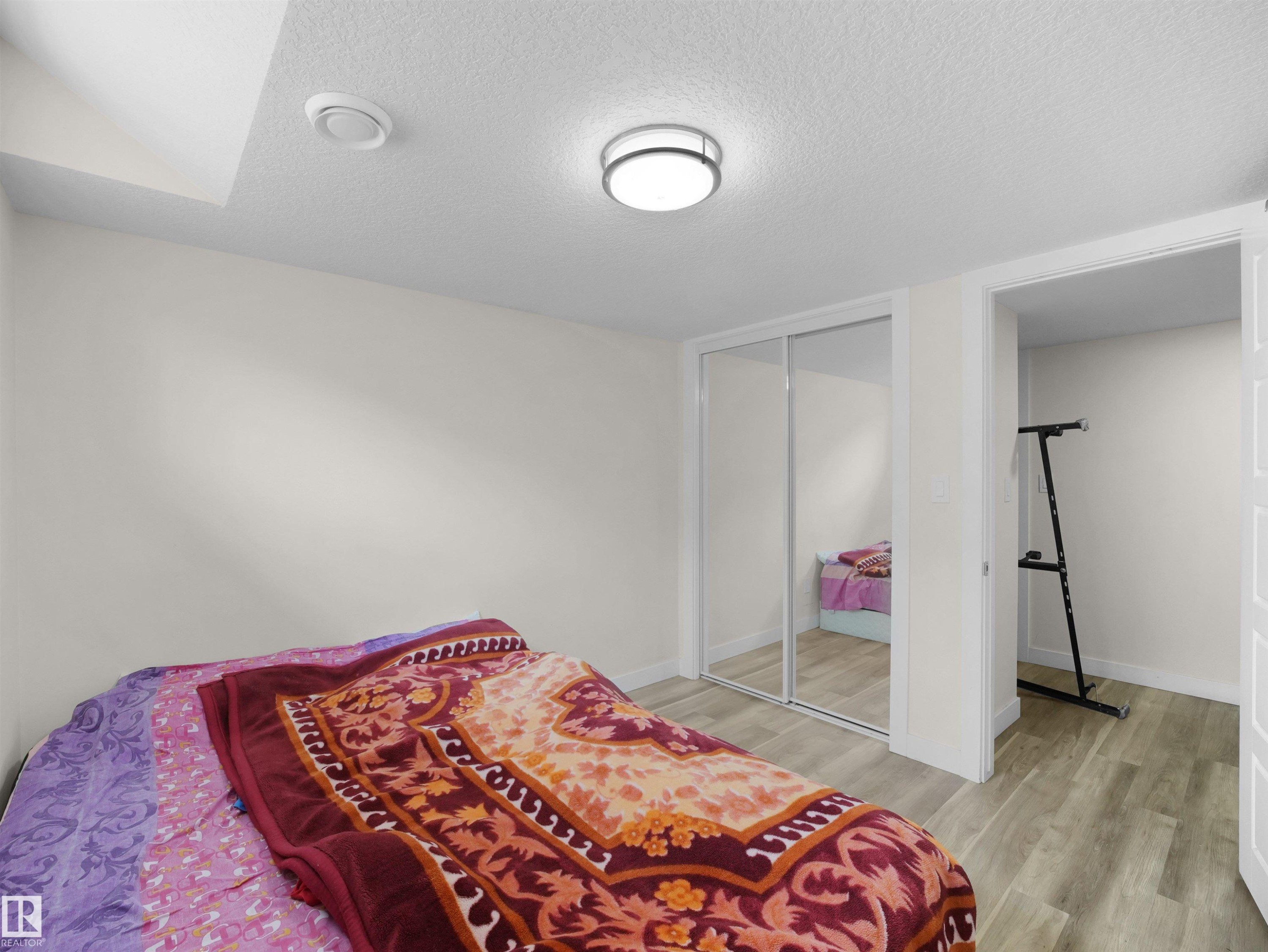 Room featuring neutral wall paint, wood-finish flooring, and a flush-mount ceiling light fixture - 3247 15 Avenue Nw, Edmonton, AB