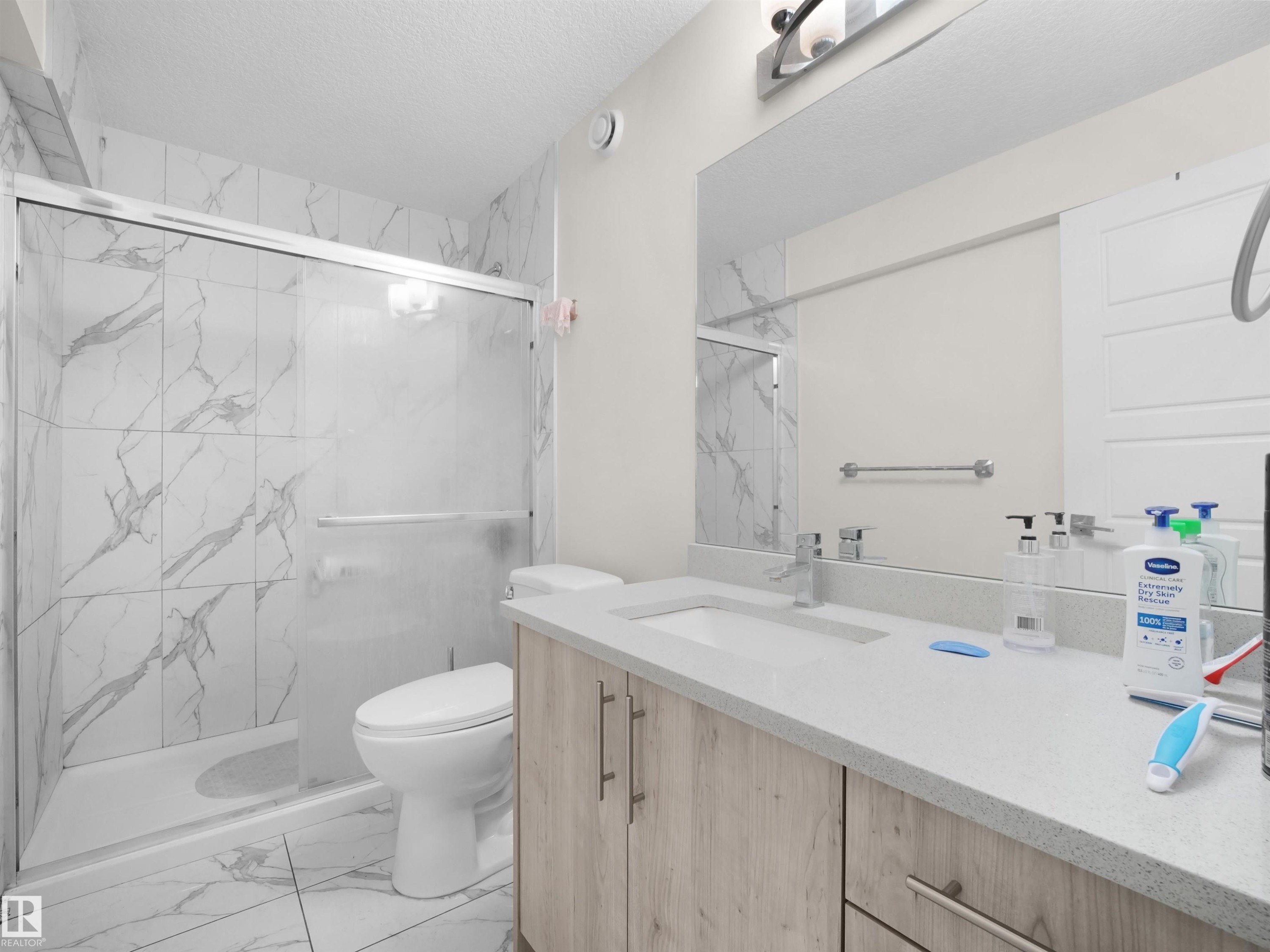 Bathroom featuring a single vanity with wood-finish cabinetry and a light-toned countertop - 3247 15 Avenue Nw, Edmonton, AB