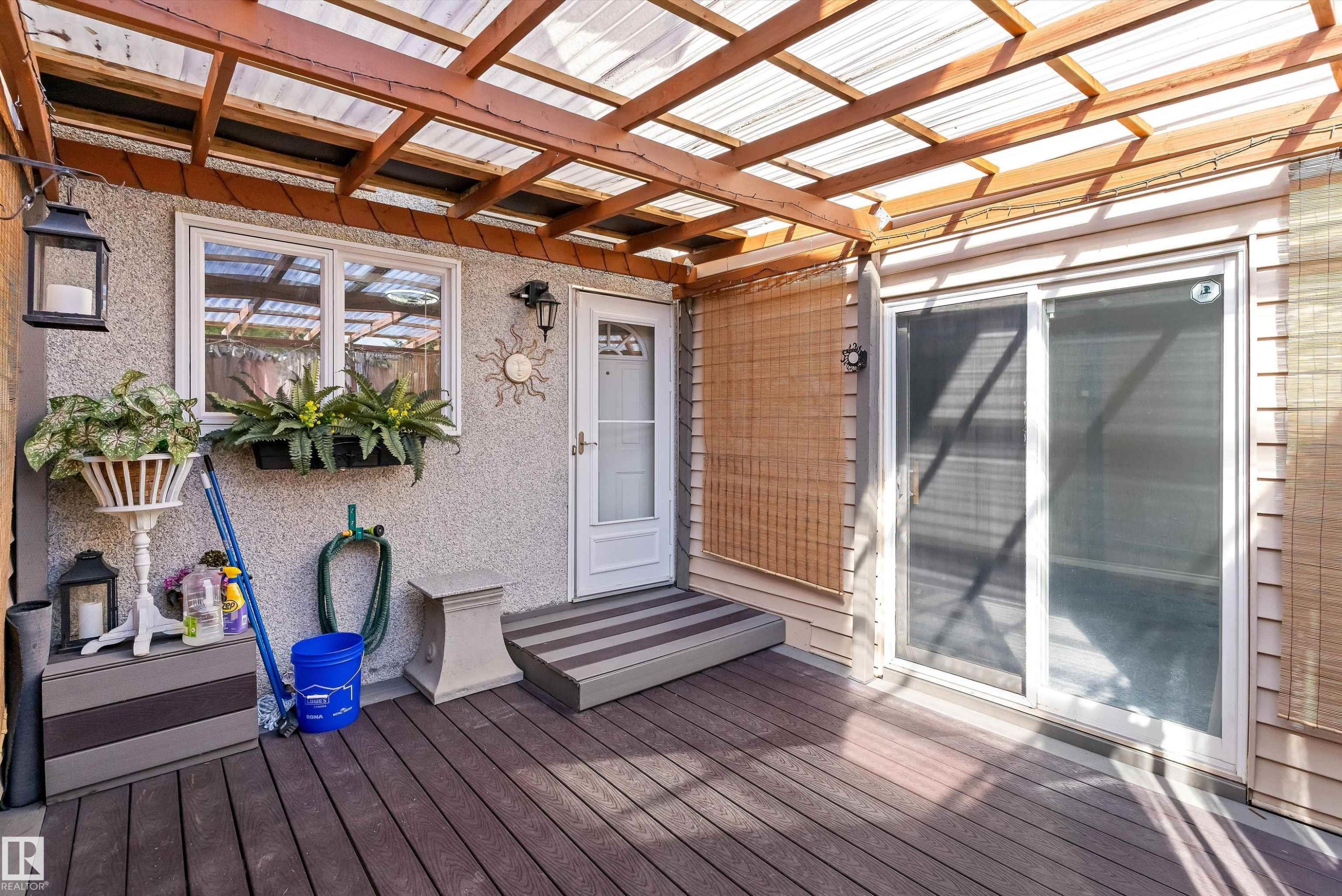 Covered patio featuring a translucent roof, wood-finish decking, and a sliding glass door - 6734 36A Avenue, Edmonton, AB - Outdoor With Deck Patio Veranda With Exterior