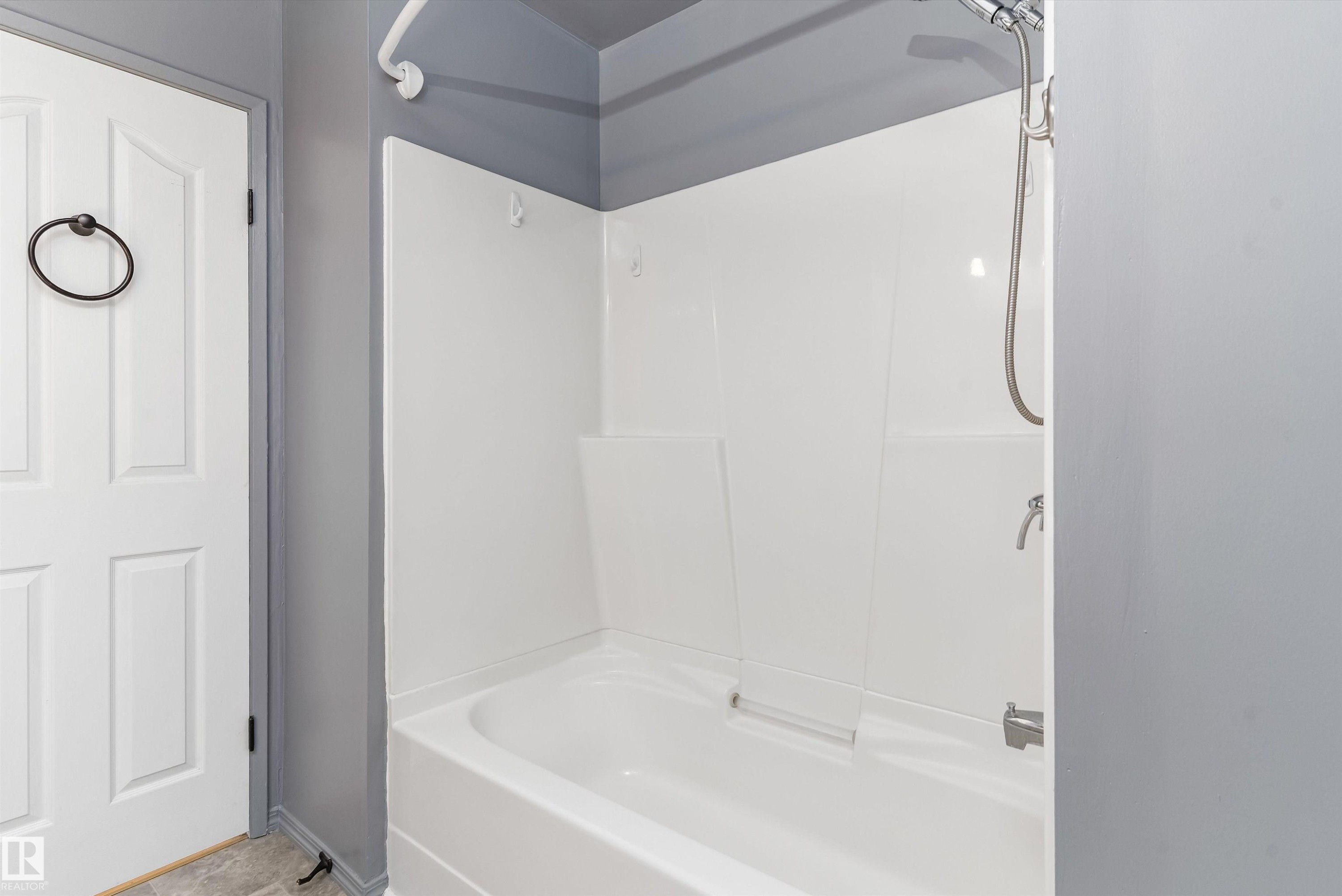 Tub and shower combination featuring white surround panels, chrome fixtures, and a curved shower rod - 6734 36A Avenue, Edmonton, AB - Indoor Photo Showing Bathroom