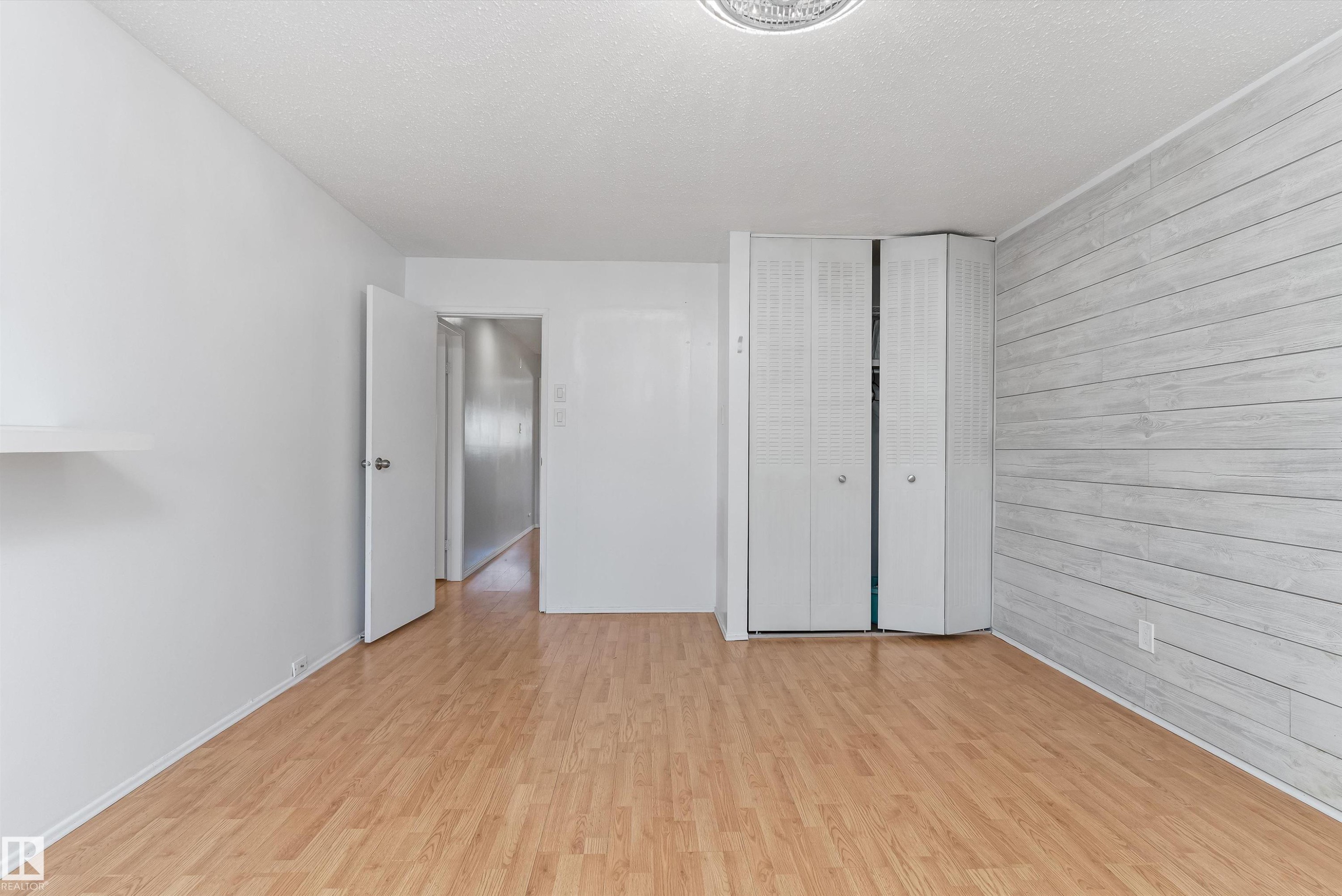 Room featuring wood-finish flooring, white walls, and a feature wall with horizontal paneling - 6734 36A Avenue, Edmonton, AB - Indoor Photo Showing Other Room