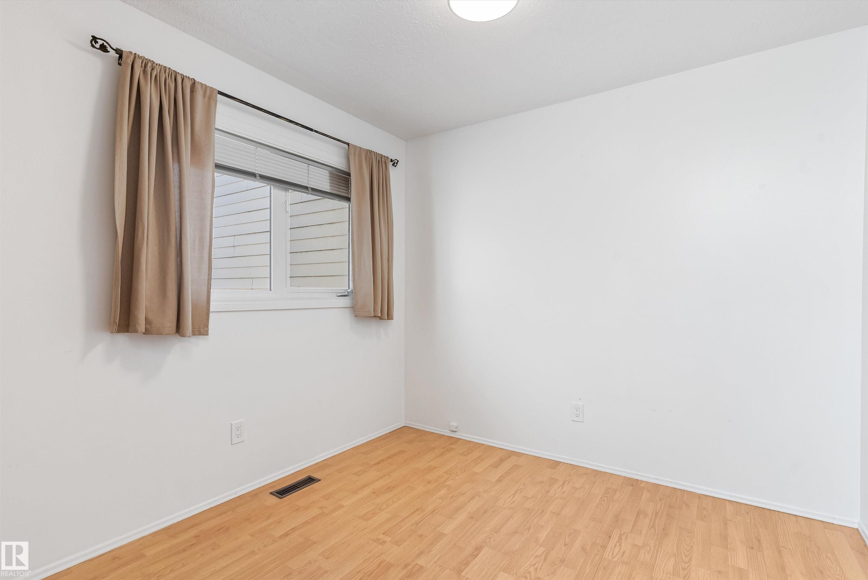 Bright room featuring wood-finish flooring, a white window frame, and a flush-mount ceiling light fixture - 6734 36A Avenue, Edmonton, AB - Indoor Photo Showing Other Room
