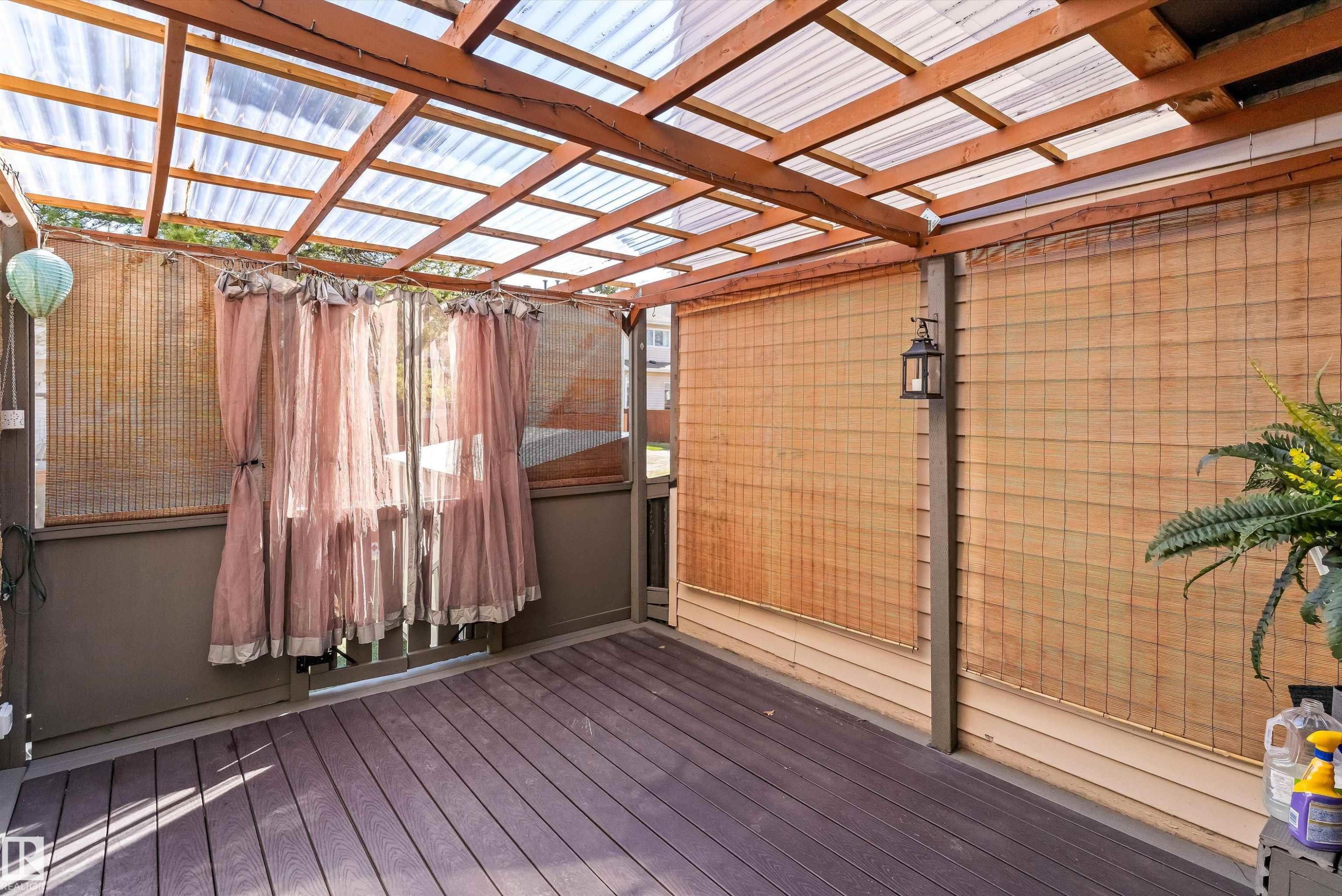 Covered outdoor patio featuring a wood-frame translucent roof, composite decking, and natural fiber privacy screens - 6734 36A Avenue, Edmonton, AB - Indoor Photo Showing Other Room
