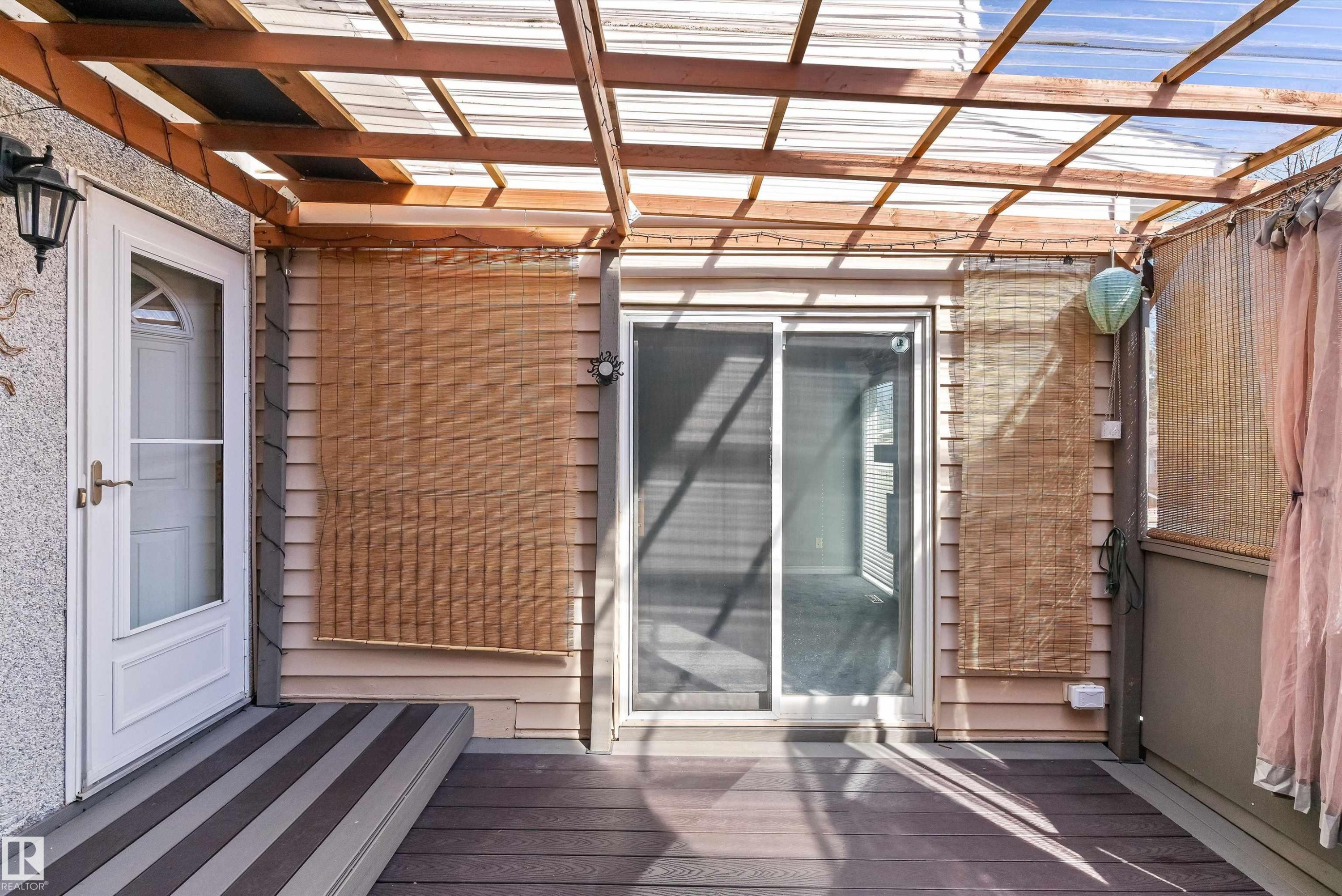 Covered outdoor patio featuring composite decking, a clear panel roof structure, and a sliding glass door - 6734 36A Avenue, Edmonton, AB - Outdoor With Exterior
