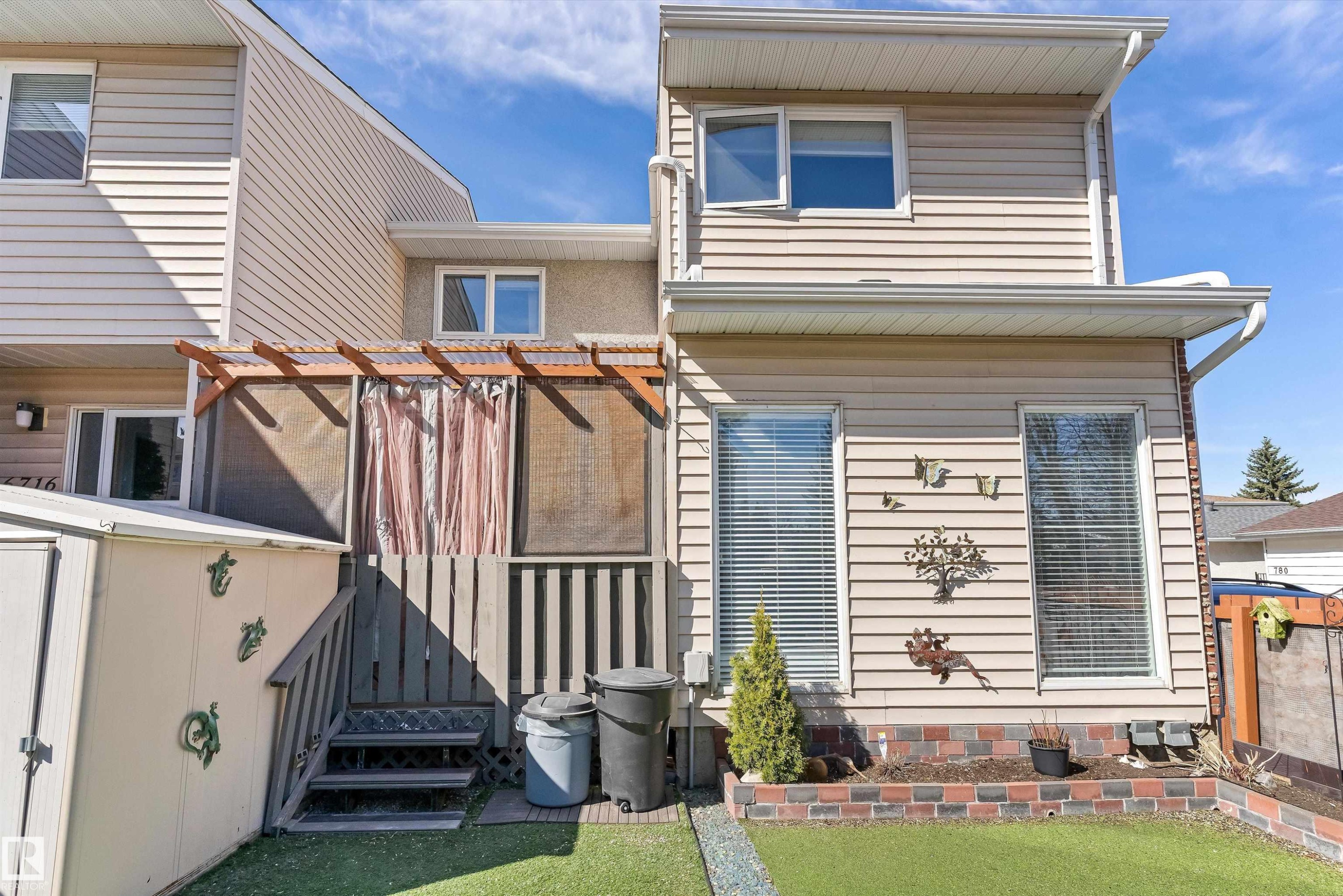 Rear exterior featuring horizontal siding, a ground-level patio area, two upper-level windows, and a lower-level window - 6734 36A Avenue, Edmonton, AB - Outdoor With Exterior
