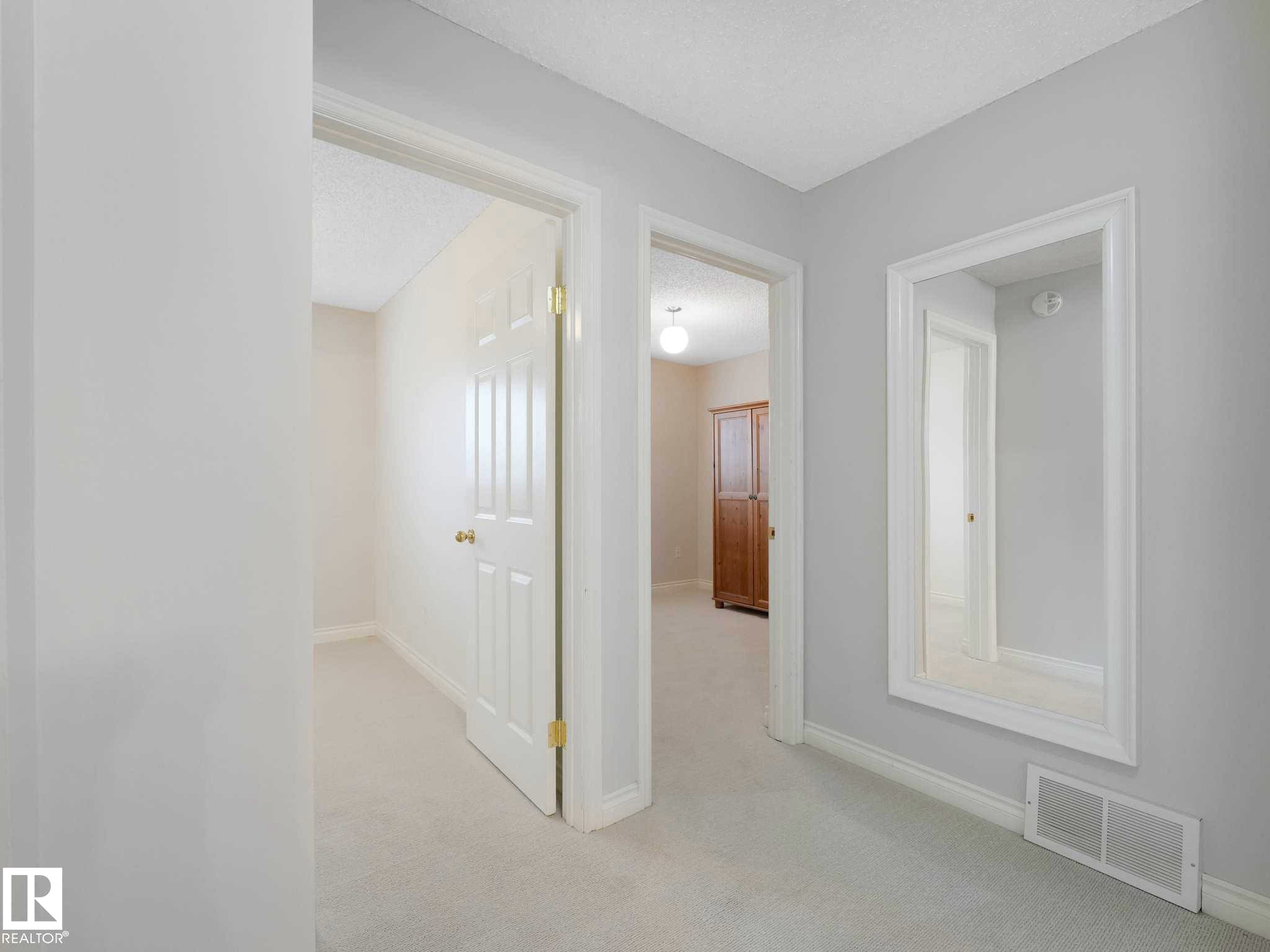 Light gray wall paint with white trim, light-toned carpet flooring, white interior doors, and a built-in wall mirror - 4011 104 Street, Edmonton, AB - Indoor Photo Showing Other Room