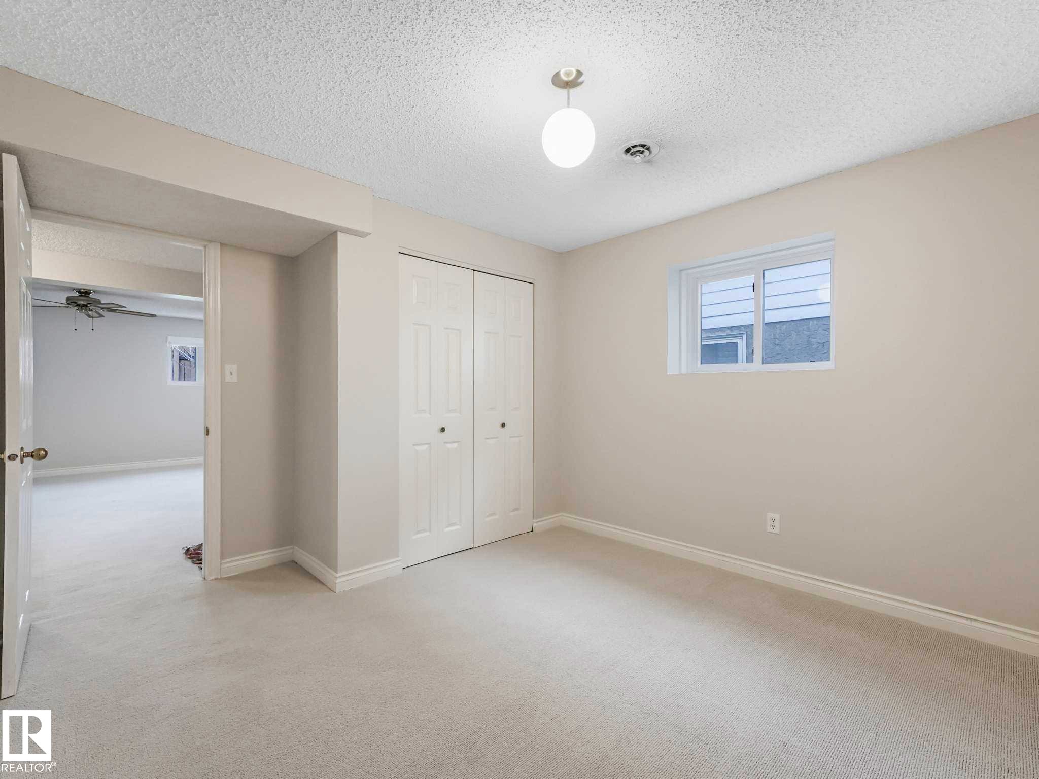 Carpeted room featuring a double bi-fold closet, a single window, and a ceiling-mounted light fixture - 4011 104 Street, Edmonton, AB - Indoor Photo Showing Other Room
