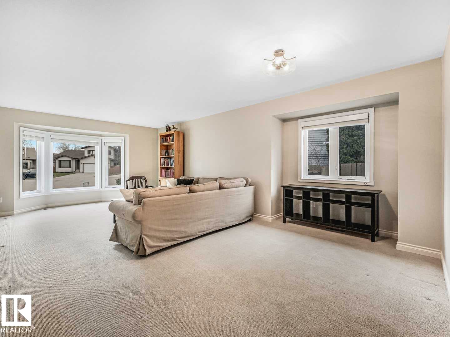 Bright living area featuring a large bay window, neutral carpet, and recessed wall niche with window - 4011 104 Street, Edmonton, AB - Indoor