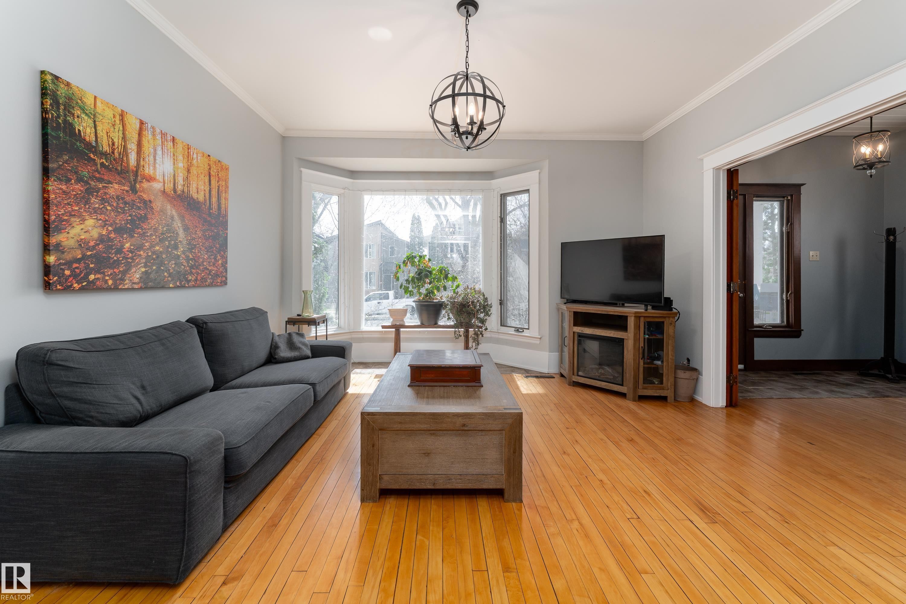 Bright and sunny living room with bay window and birch hardwood floors - 10956 81 Avenue, Edmonton, AB - Indoor Photo Showing Living Room