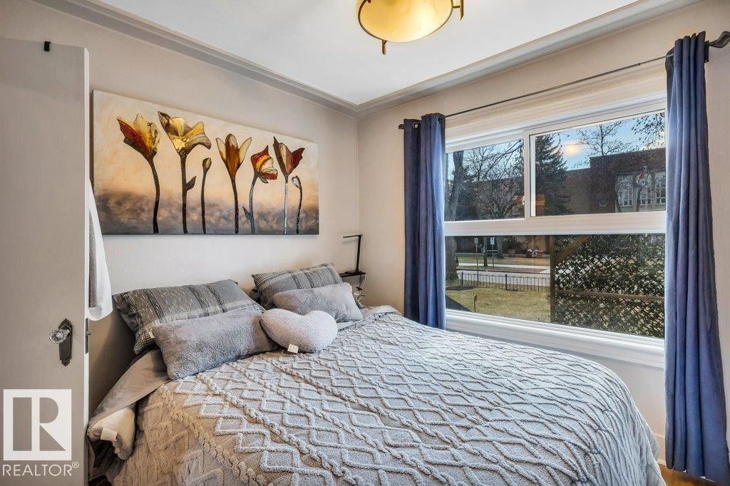 Spacious room featuring a large window, crown molding, and a built-in ceiling light fixture - 11445 68 Street, Edmonton, AB - Indoor Photo Showing Bedroom