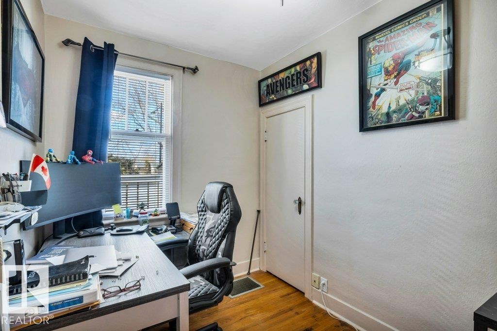 Room featuring wood-finish flooring, a white trim window with blinds, and a white door with dark hardware - 11445 68 Street, Edmonton, AB - Indoor Photo Showing Office