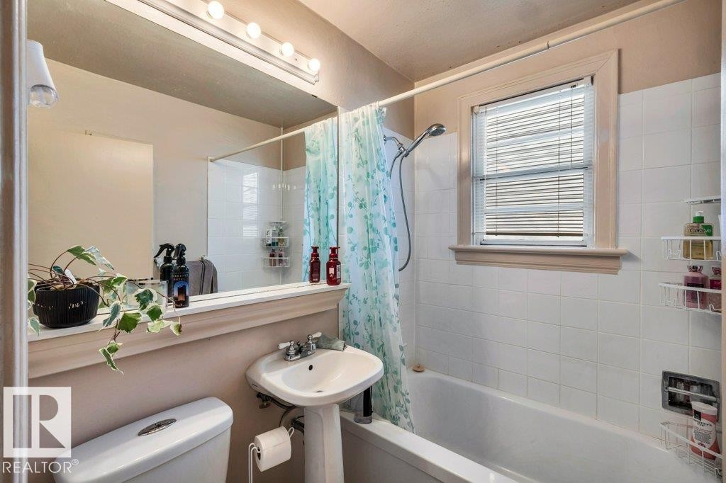 Full bathroom featuring a pedestal sink, a toilet, and a bathtub with an integrated shower - 11445 68 Street, Edmonton, AB - Indoor Photo Showing Bathroom