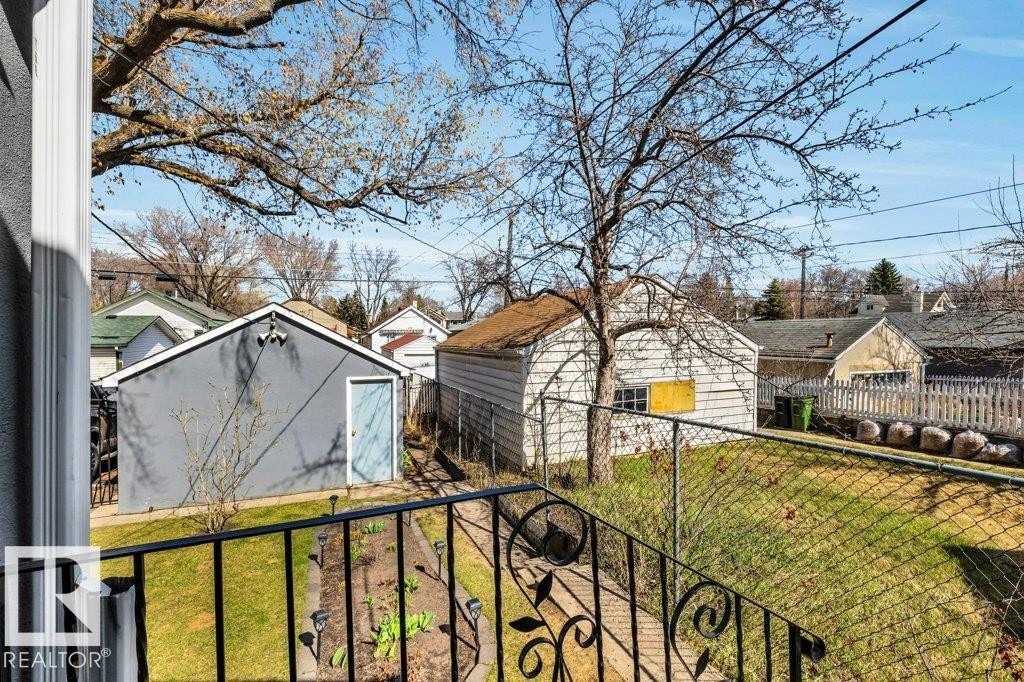 Rear yard with manicured lawn, chain-link fencing, and established trees - 11445 68 Street, Edmonton, AB - Outdoor