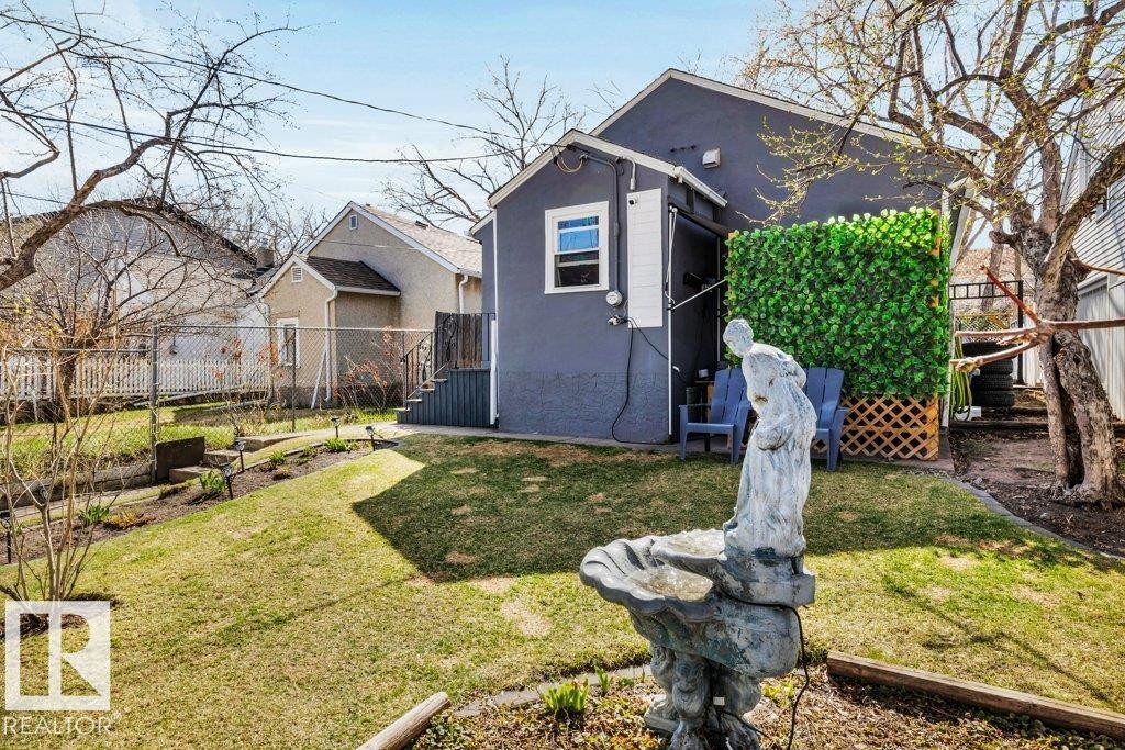 Expansive backyard featuring a manicured lawn, established landscaping, and a decorative garden fountain - 11445 68 Street, Edmonton, AB - Outdoor