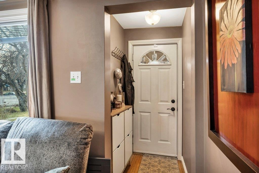 Entryway featuring a white paneled door with an arched glass insert, black hardware, and an overhead flush-mount light fixture - 11445 68 Street, Edmonton, AB - Indoor