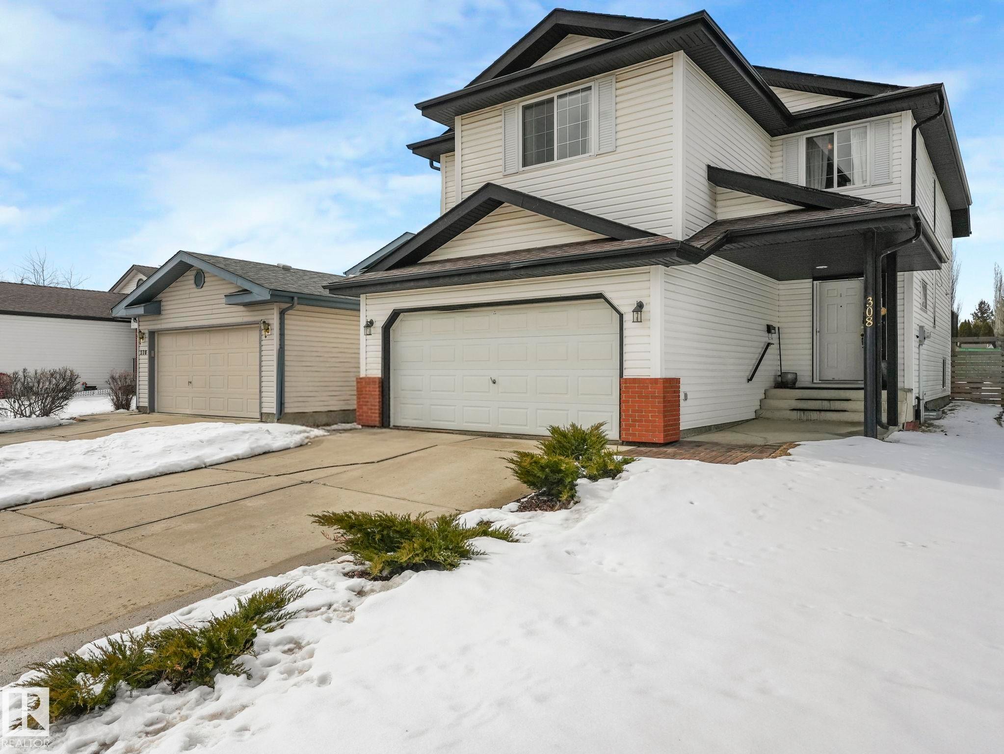 The property features a white exterior with dark trim, a two-car garage, and a covered entryway - 308 Beringer Crescent, Edmonton, AB - Outdoor