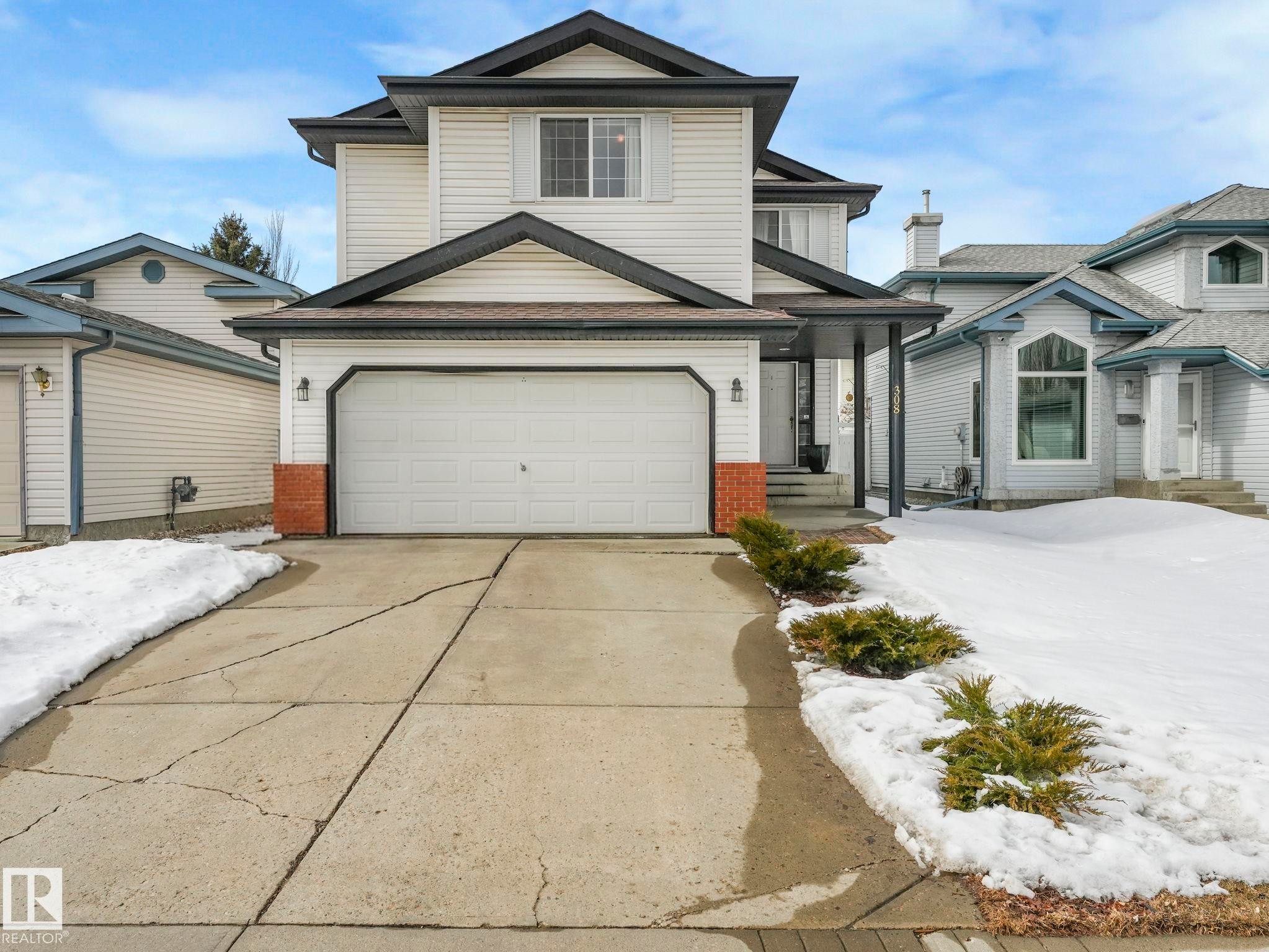 The property features a two-story exterior with light-colored siding, a dark roof, and an attached two-car garage - 308 Beringer Crescent, Edmonton, AB - Outdoor With Facade